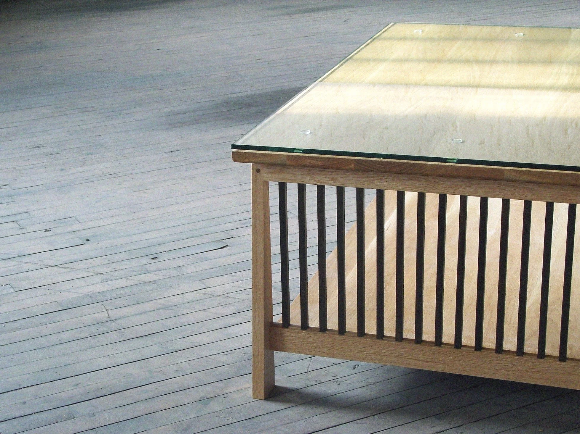 A wooden table with a glass top on a wooden floor.