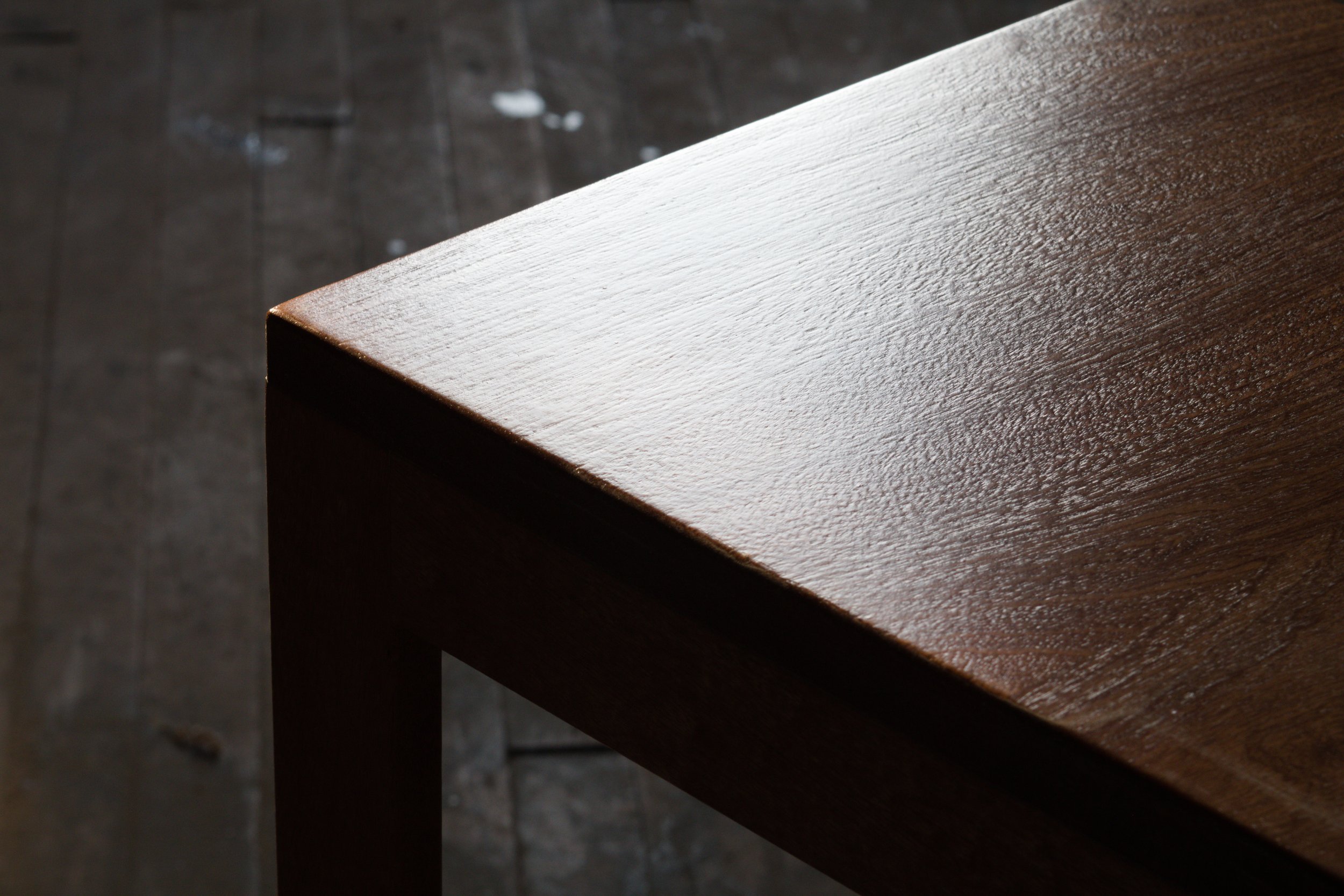 Close-up of a wooden table corner with a smooth, stained finish.