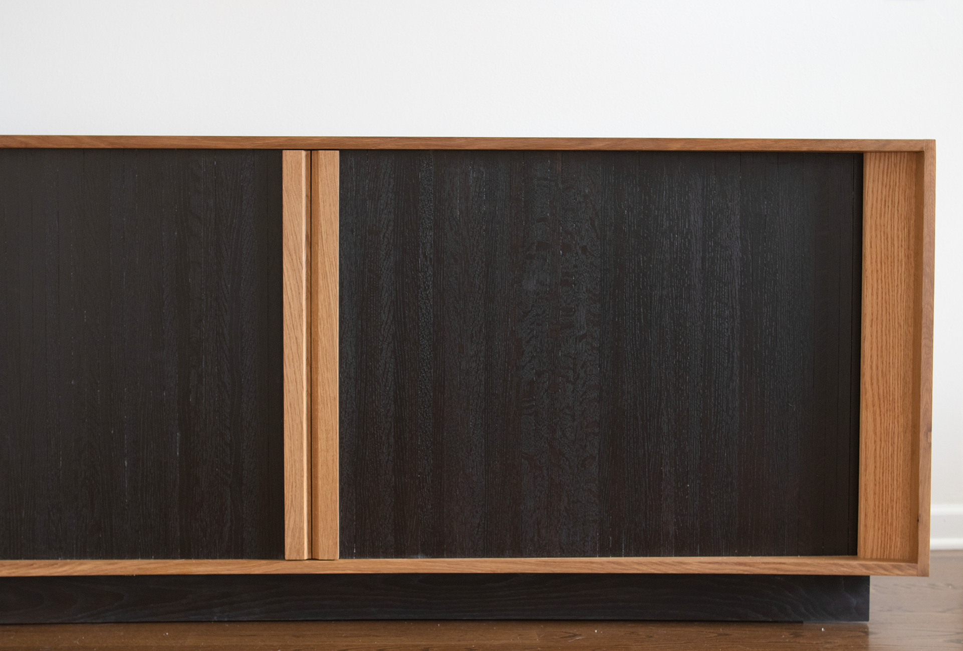 Close-up of a wooden cabinet with dark sliding doors and a natural wood frame.
