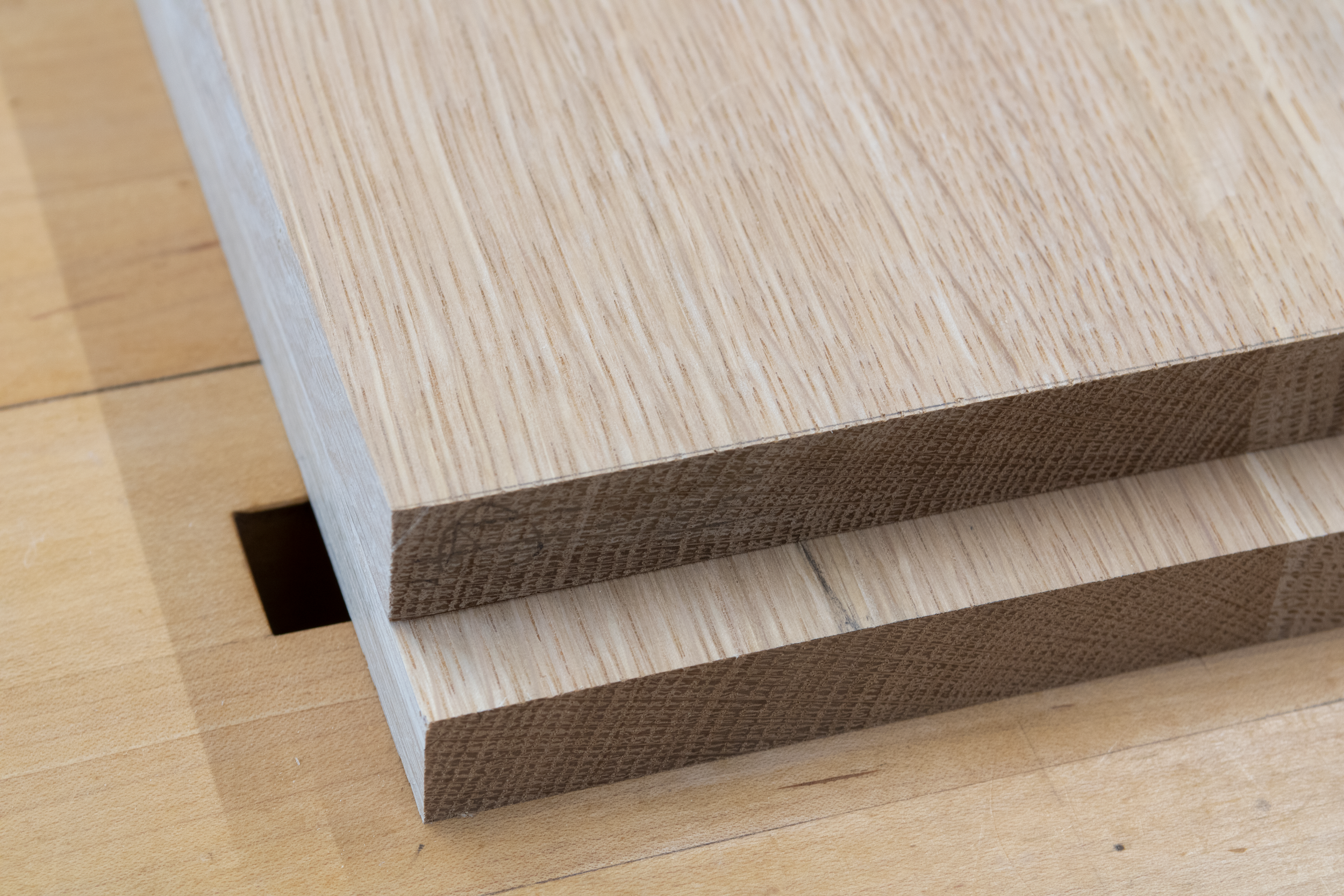 Close-up of stacked wooden blocks with a smooth, light-colored top and textured, darker sides on a wooden surface.
