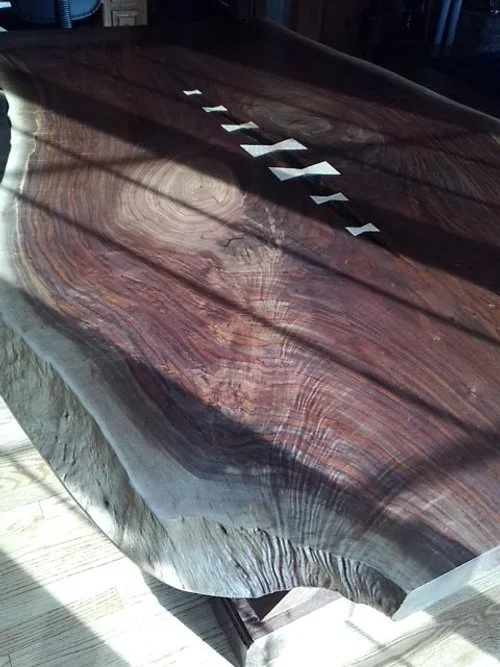 A close-up of a wooden table with a visible wood grain pattern and a row of white arrow-shaped objects placed along the center.