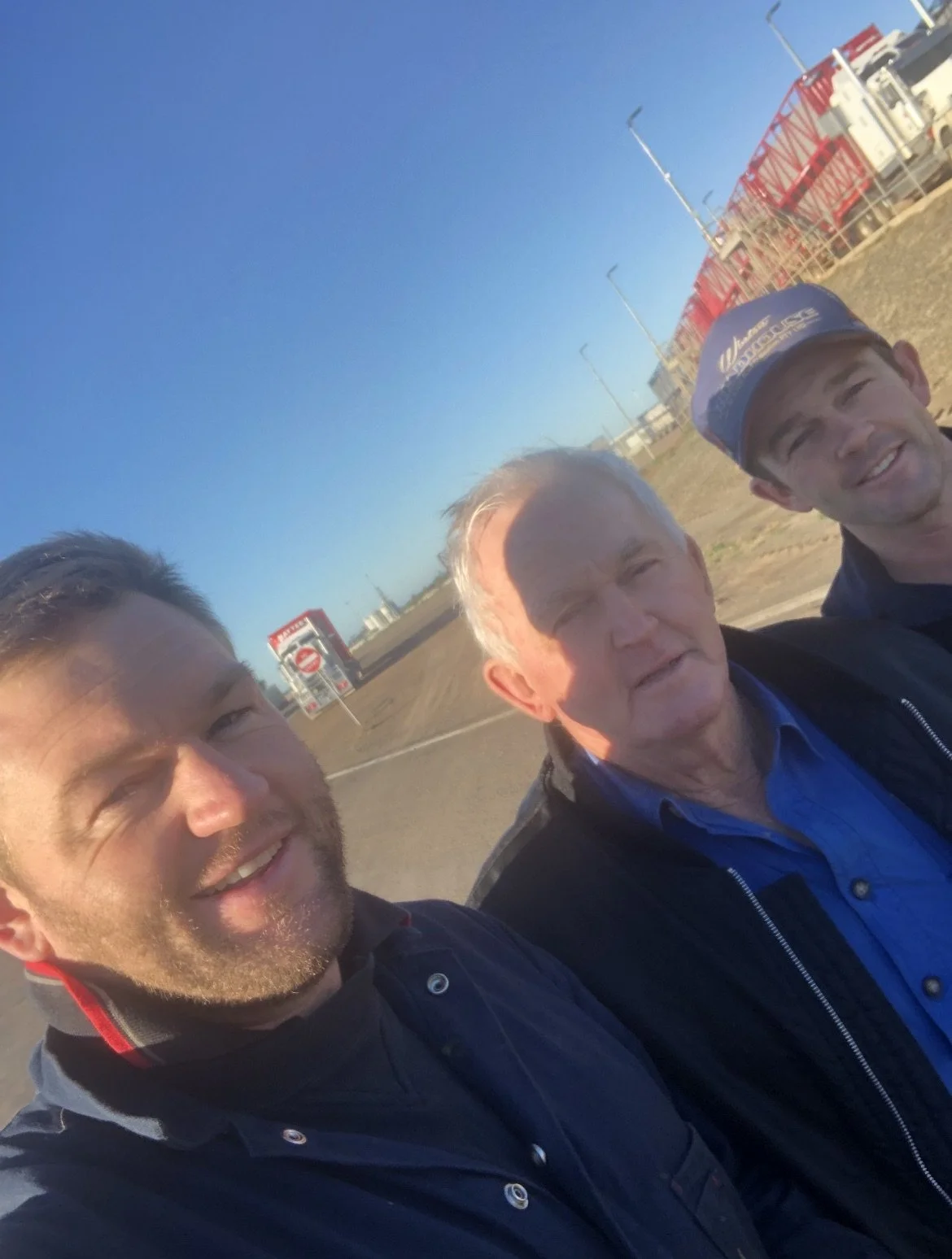 David Hayter with Sons, Thomas and Jeremy picked at Roma Sales Yards QLD in 2021 with trucks and road trains in the background.jpeg