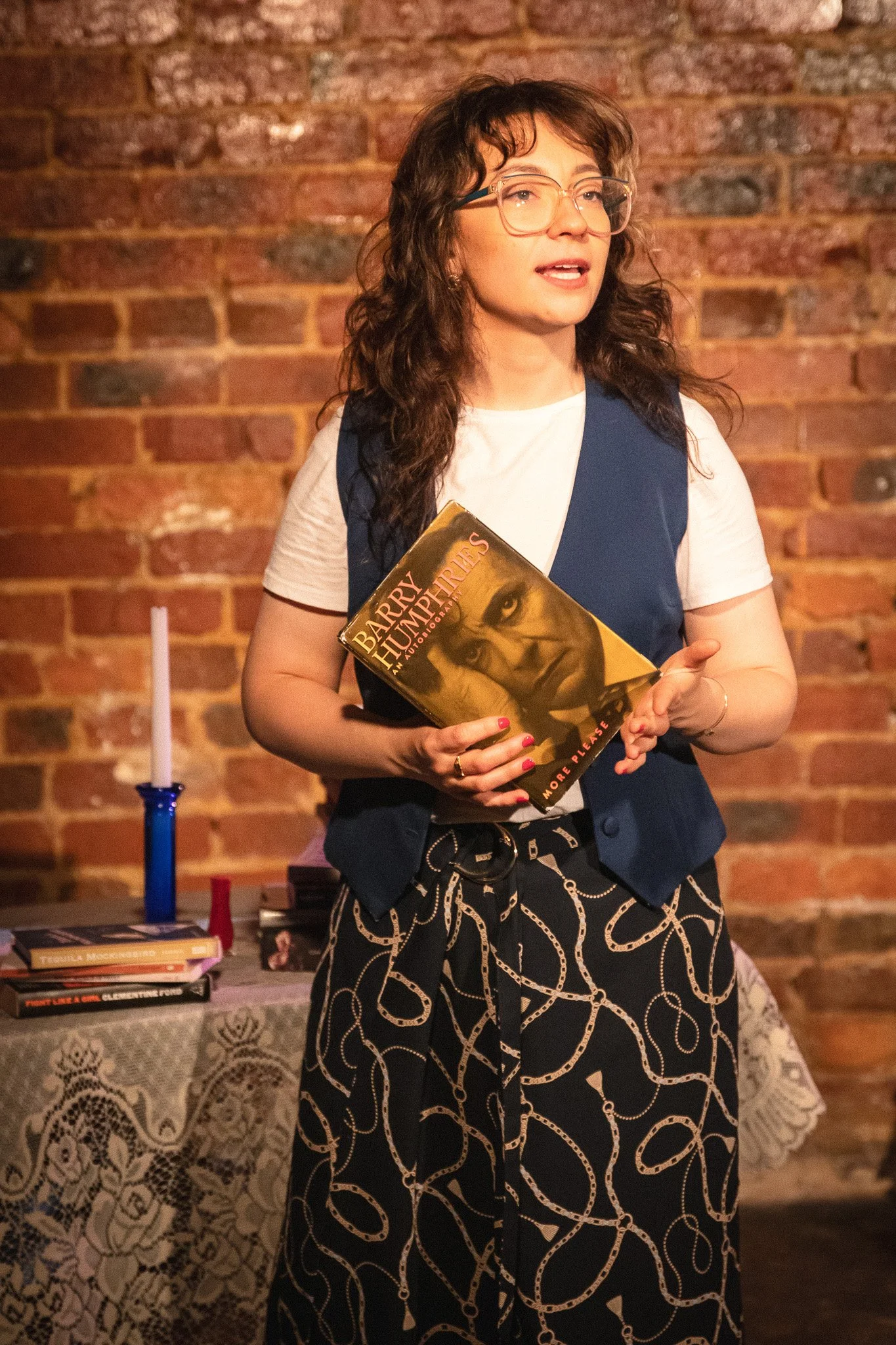 Atmospheric image from “NUSIA” by A Ry Presentation, showing the actor in a reflective moment as she shares a narrative rooted in culture, resilience, and self-discovery. Minimalist staging draws attention to her storytelling