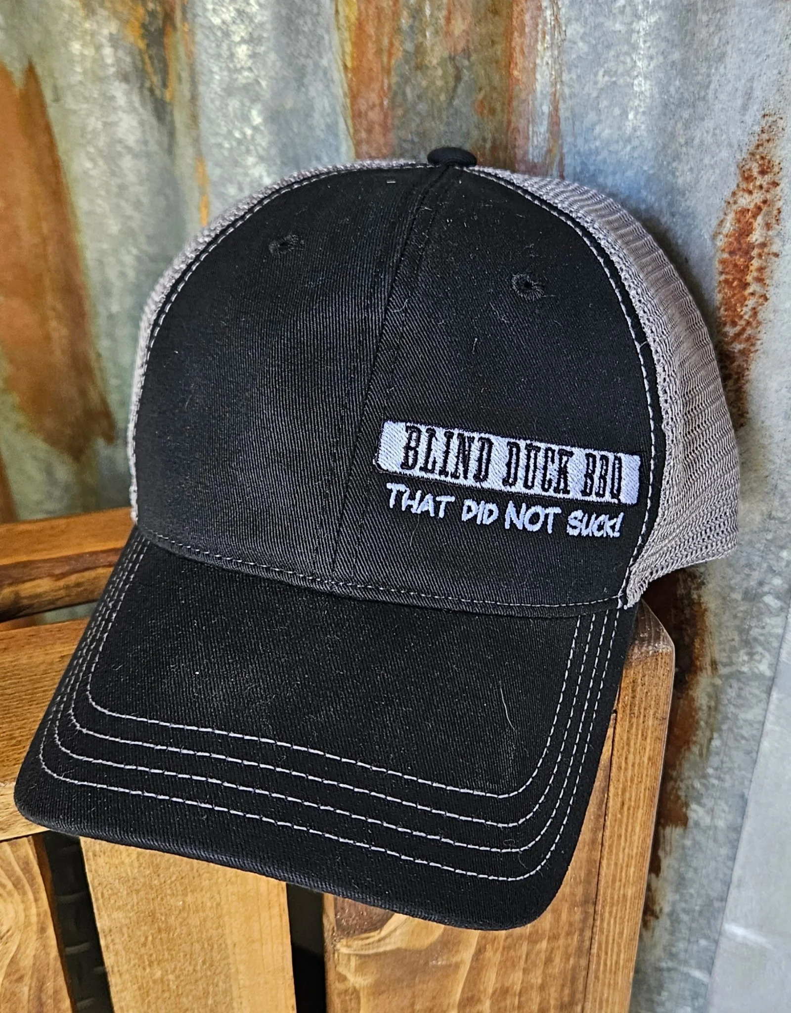 Black and gray trucker cap with a white patch that says "Blind Duck BBQ That Did Not Suck!"