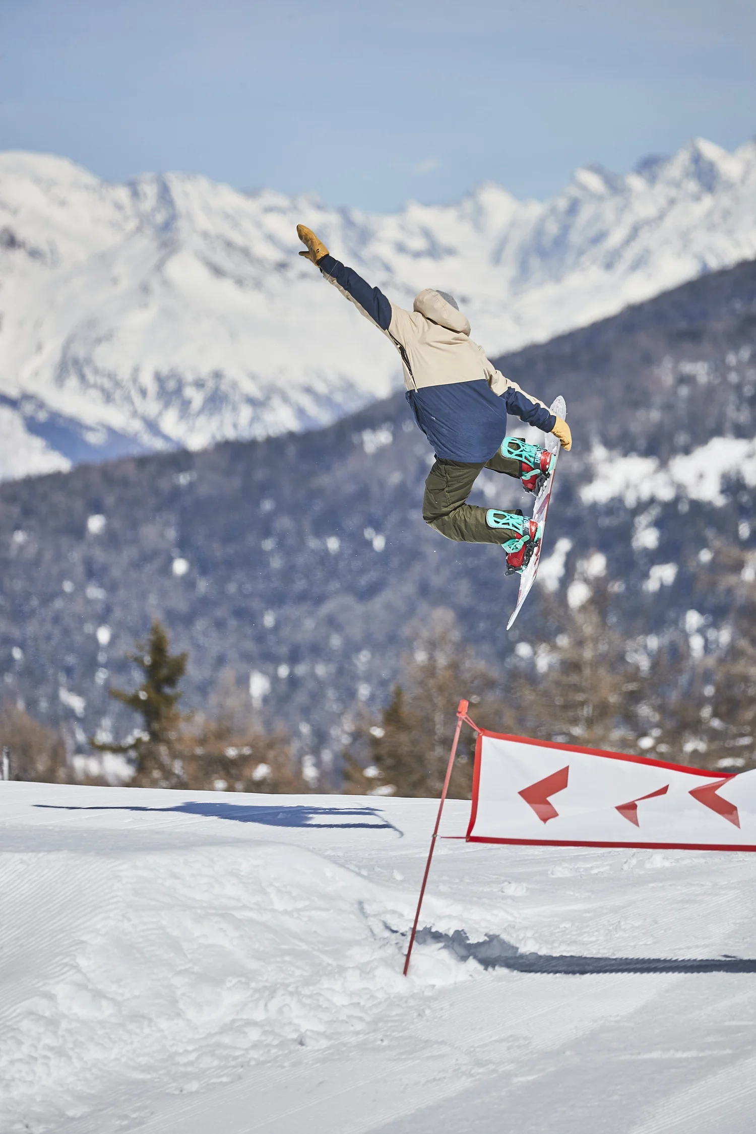 Snowboarder crossing a snowy terrain-park feature — photograph by Michaël Gramm