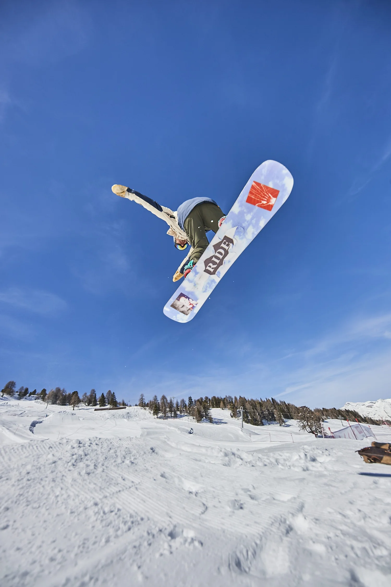 Underside of a snowboard visible during a jump — photograph by Michaël Gramm