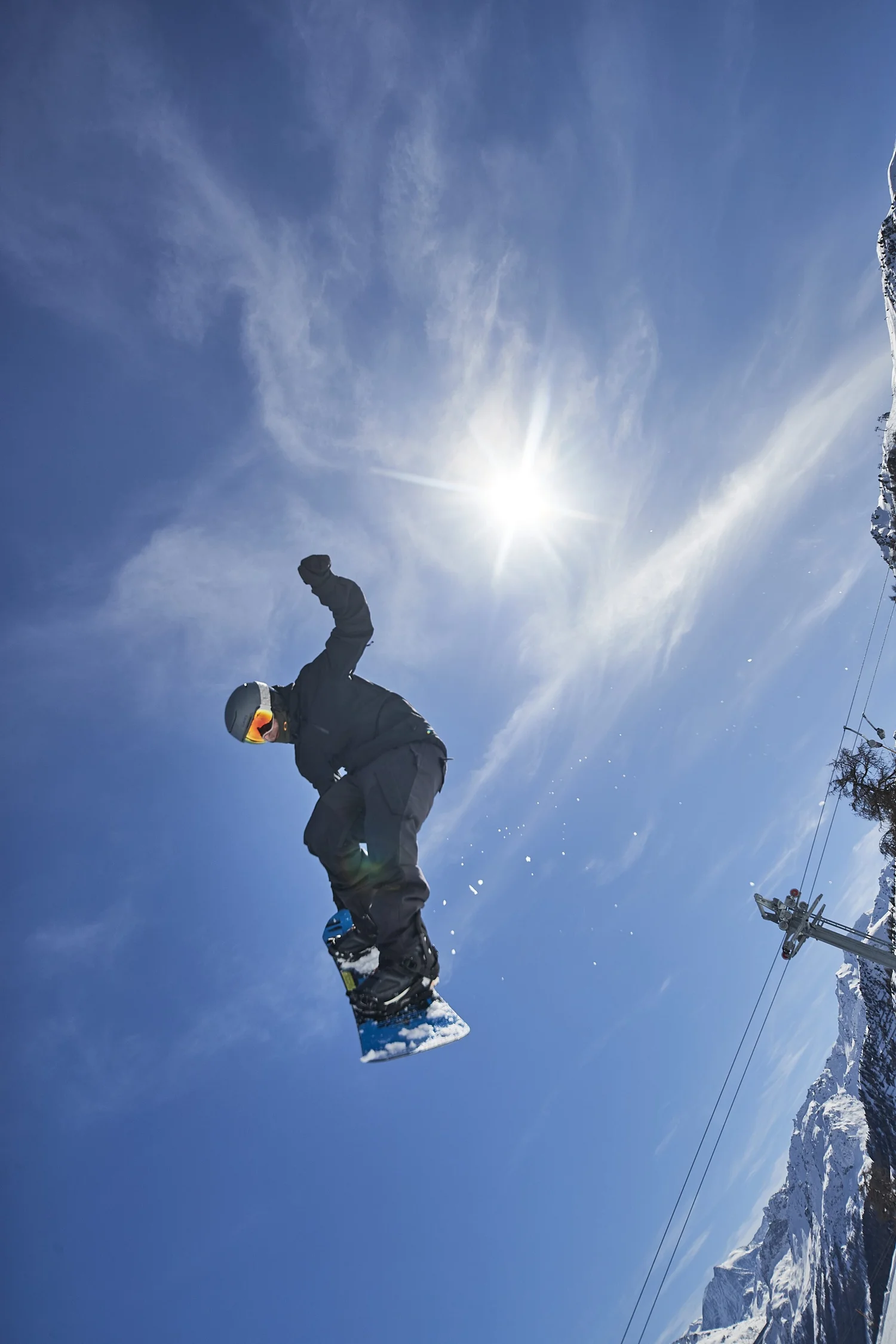 Snowboarder silhouetted beneath a bright sun — photograph by Michaël Gramm