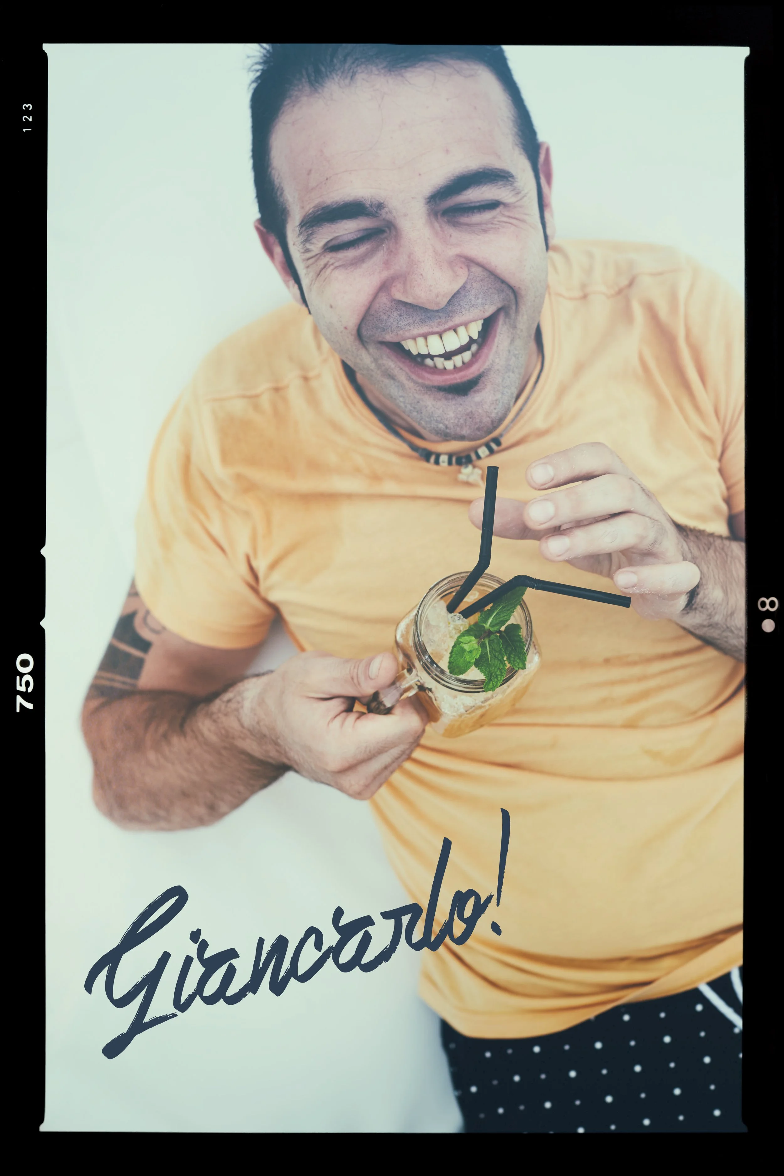 A man in a yellow T-shirt holding a mason jar margarita with mint and ice, smiling and looking at the camera, with the word 'Giarcão!' written on the image.