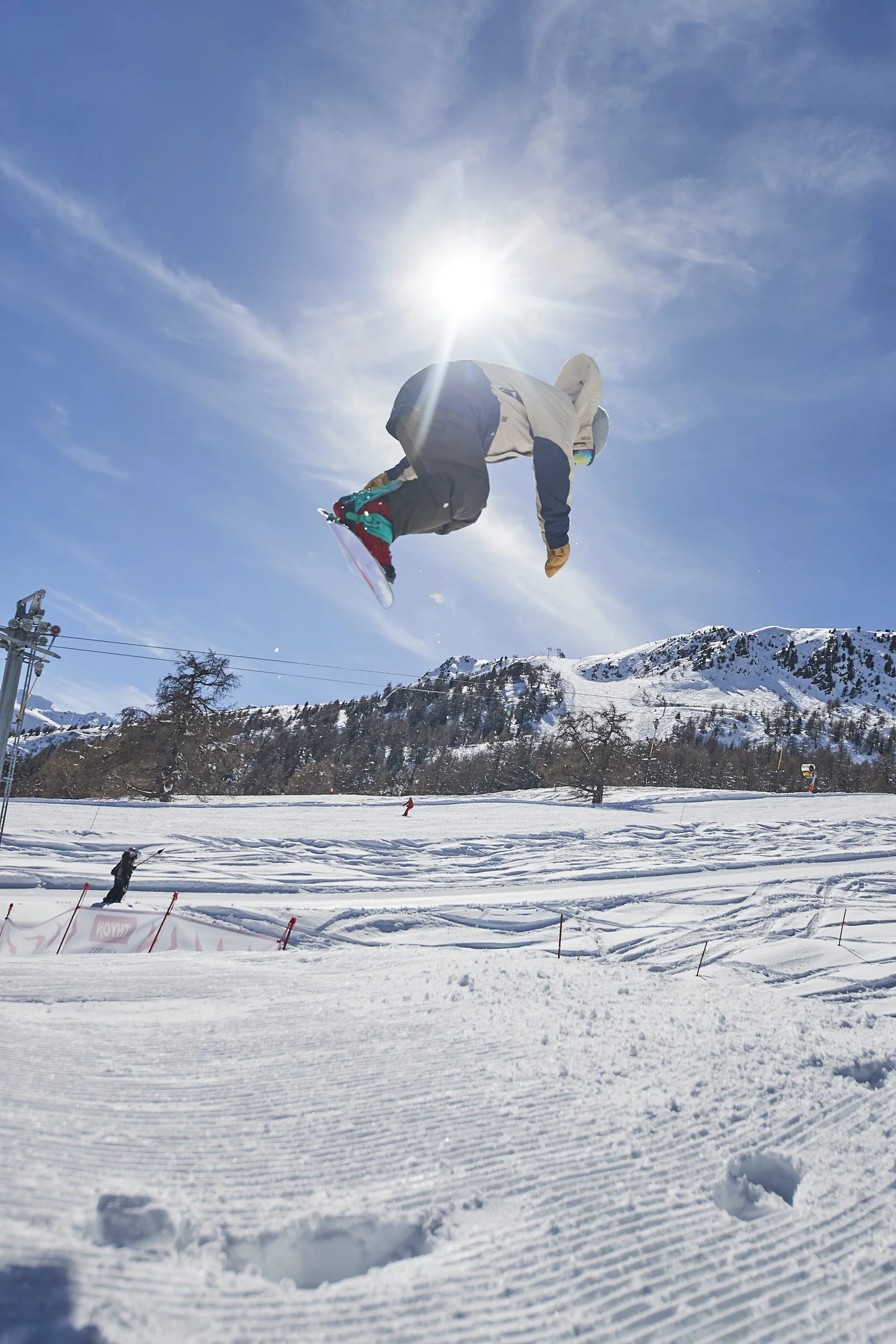 Snowboarder jumping beneath the sun — photograph by Michaël Gramm