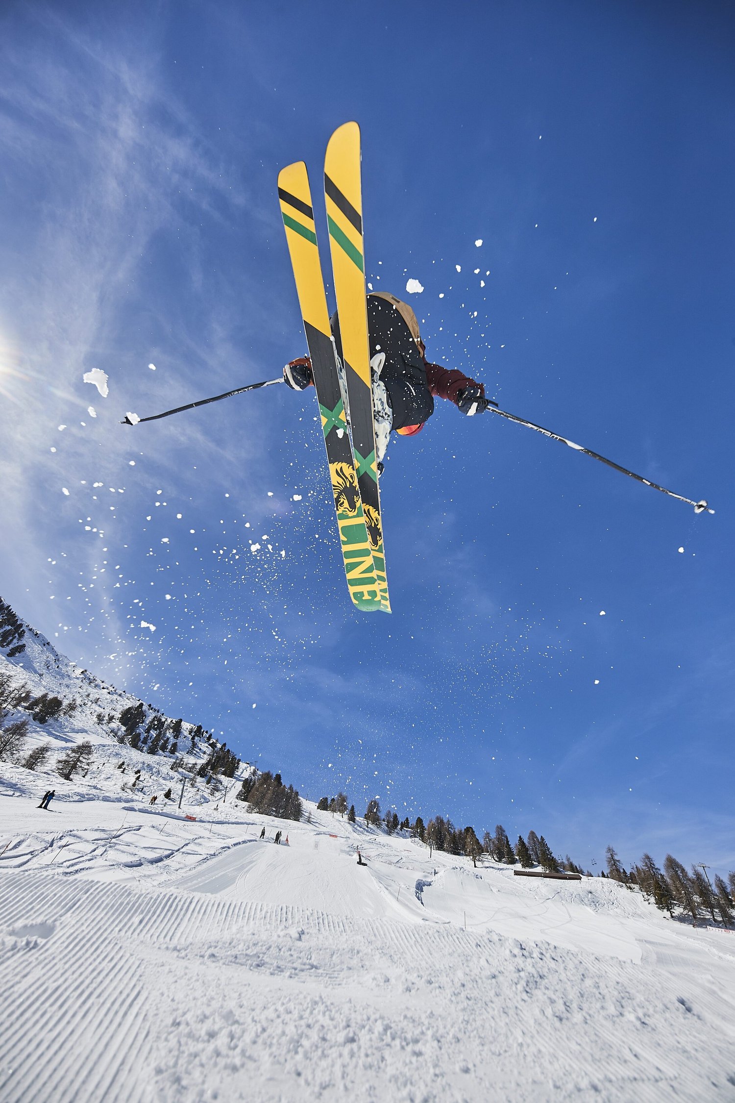 Skier with yellow skis extended above a snow ramp — photograph by Michaël Gramm