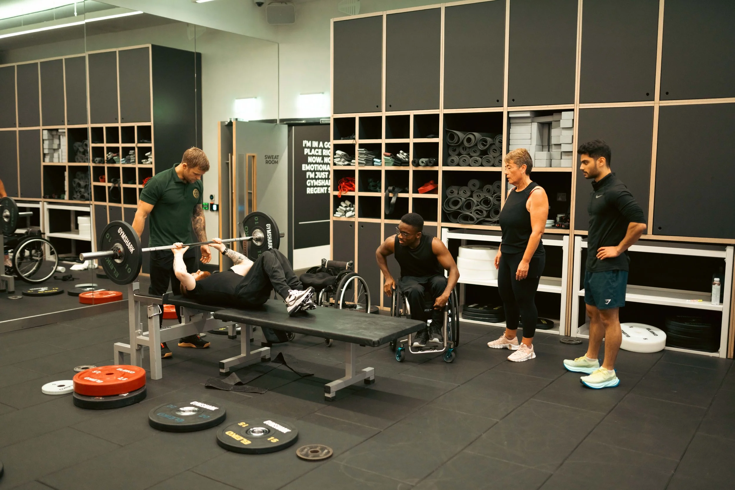 Pantheon Plymouth coach supporting an inclusive strength training session with members of different abilities, including wheelchair users, during a personalised fitness programme.