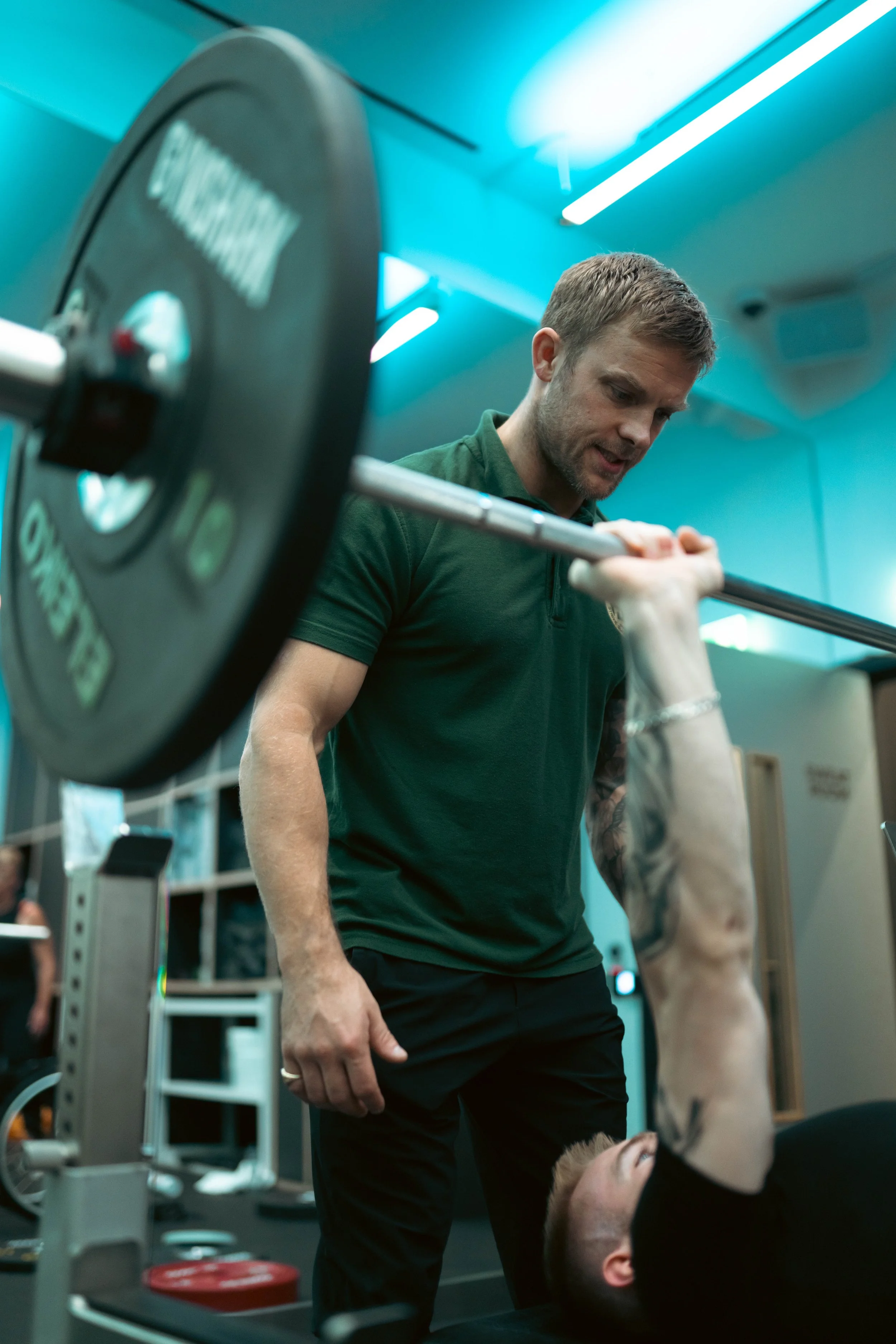 Personal trainer coaching a client through a barbell strength training exercise at Pantheon Plymouth gym, delivering one-to-one support, technique guidance and progressive fitness coaching.