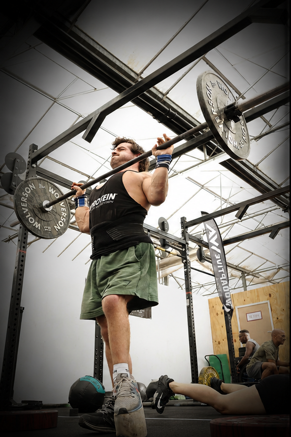 Adaptive athlete performing a barbell shoulder press during an inclusive strength training session at Pantheon Plymouth gym.