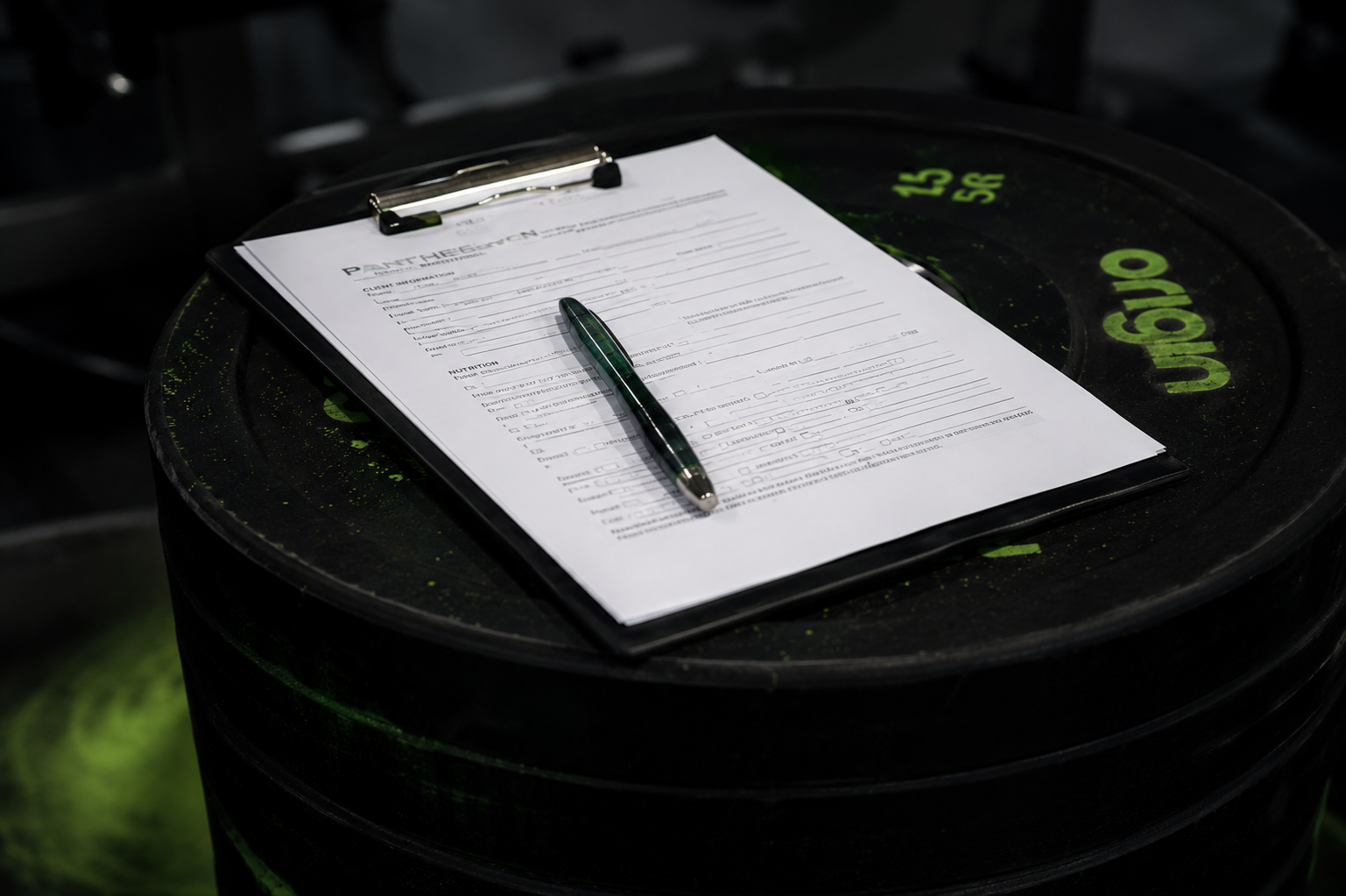 Personal training consultation form and pen placed on weight plates at Pantheon Plymouth gym, representing fitness assessments, goal setting and personalised training programmes in Plymouth, Devon.