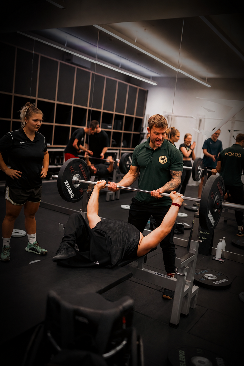 Pantheon Plymouth coach supporting a member during a bench press exercise in an inclusive gym environment, demonstrating personalised strength coaching and adaptive fitness support.