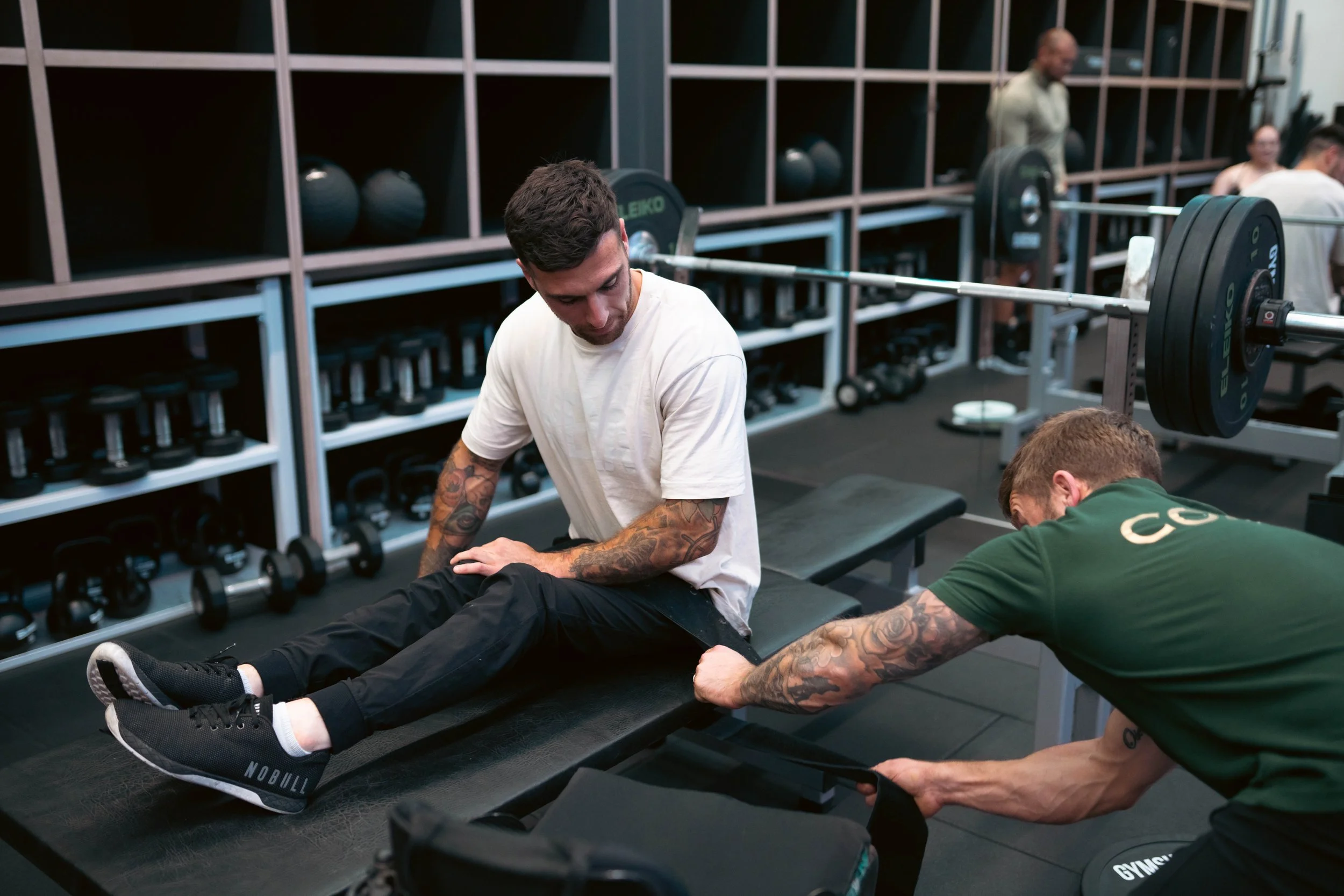 Personal training session at Pantheon Plymouth gym with a coach assisting a member during strength and rehabilitation-focused exercise. Pantheon helps members improve strength, mobility and fitness through tailored support.
