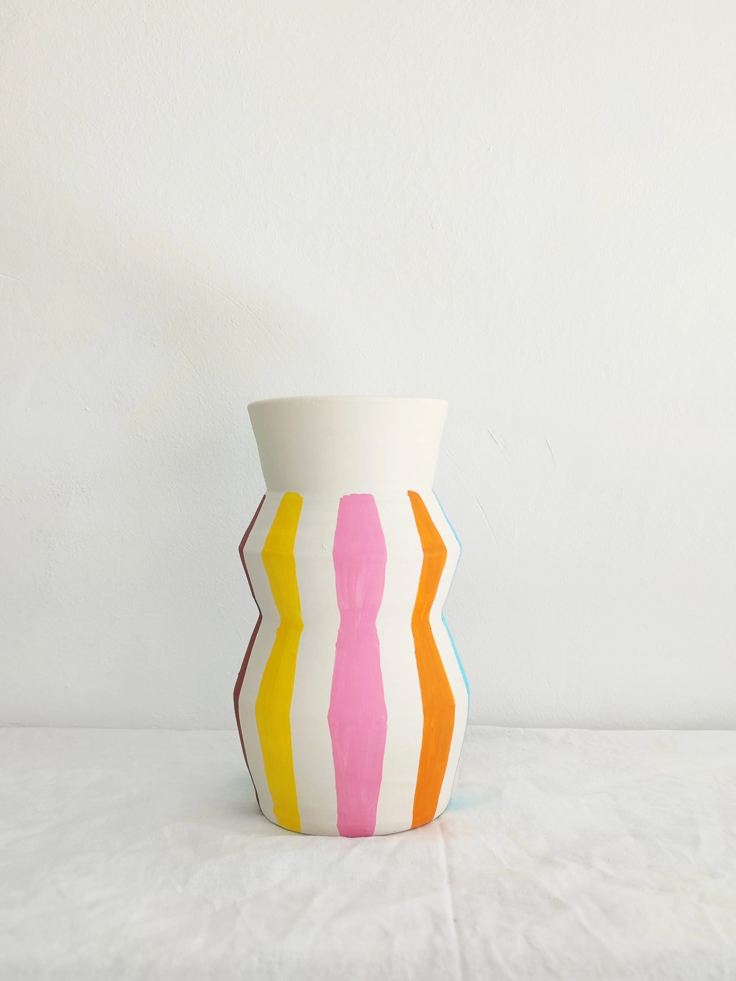 Jarrón de barro blanco hecho y decorado a mano rayas multicolor.