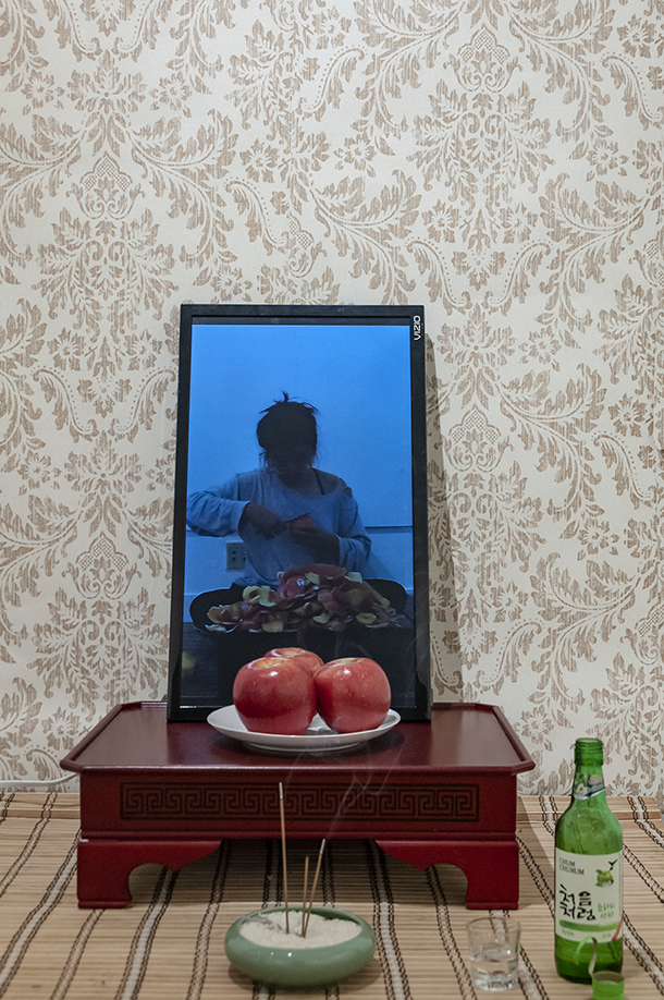  Mom, I can get married now!  Installation: performance documentation, apple soju, soju glass, incense, rice, incense holder, apples, ceramic plate, bamboo curtain, 밥상, wallpaper.  Installation view. 