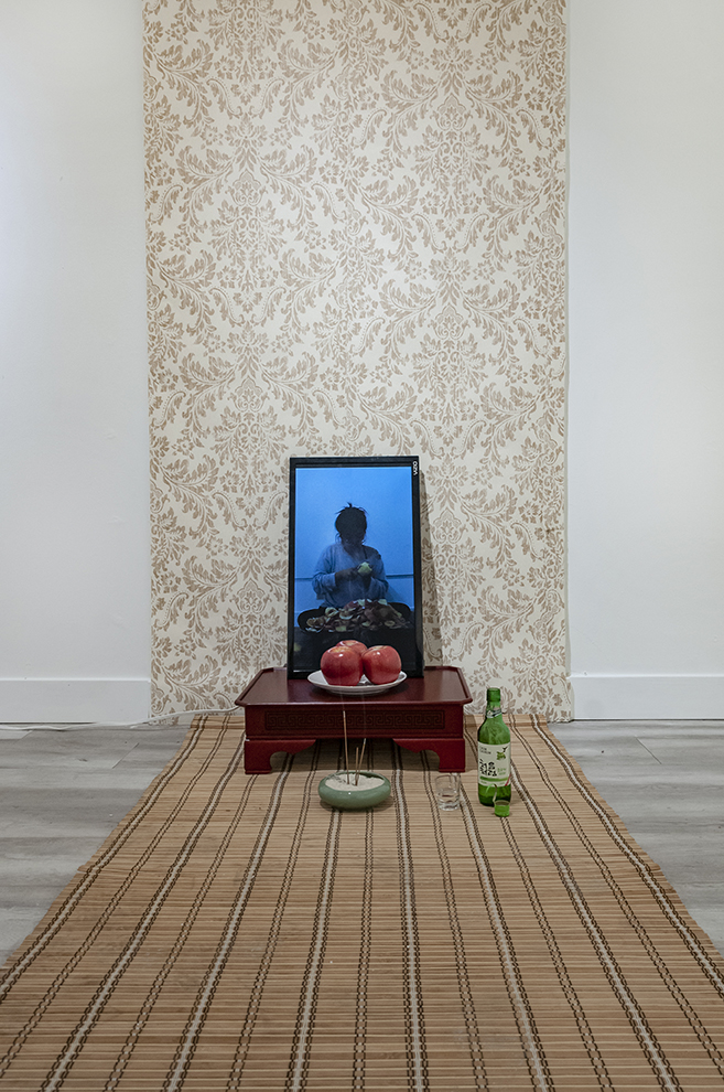  Mom, I can get married now!  Installation: performance documentation,  apple soju, soju glass, incense, rice, incense holder, apples, ceramic plate, bamboo curtain, 밥상, wallpaper.  Installation view.  