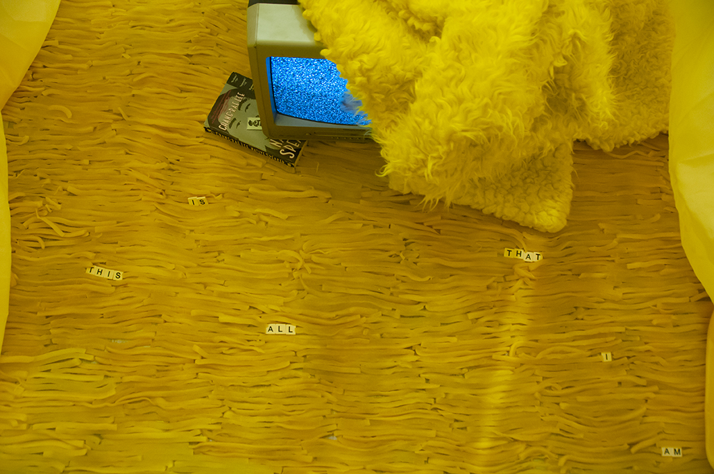 Is this | This is… Multimedia installation: yellow curtains, old television, copy of Native Speaker by Chang Rae Lee, wig, 20 packs of rectangle dan moo ji, 5 packs of circle dan moo ji, print, shag rug, scrabble letters. 120” x 240” x 240” Insta