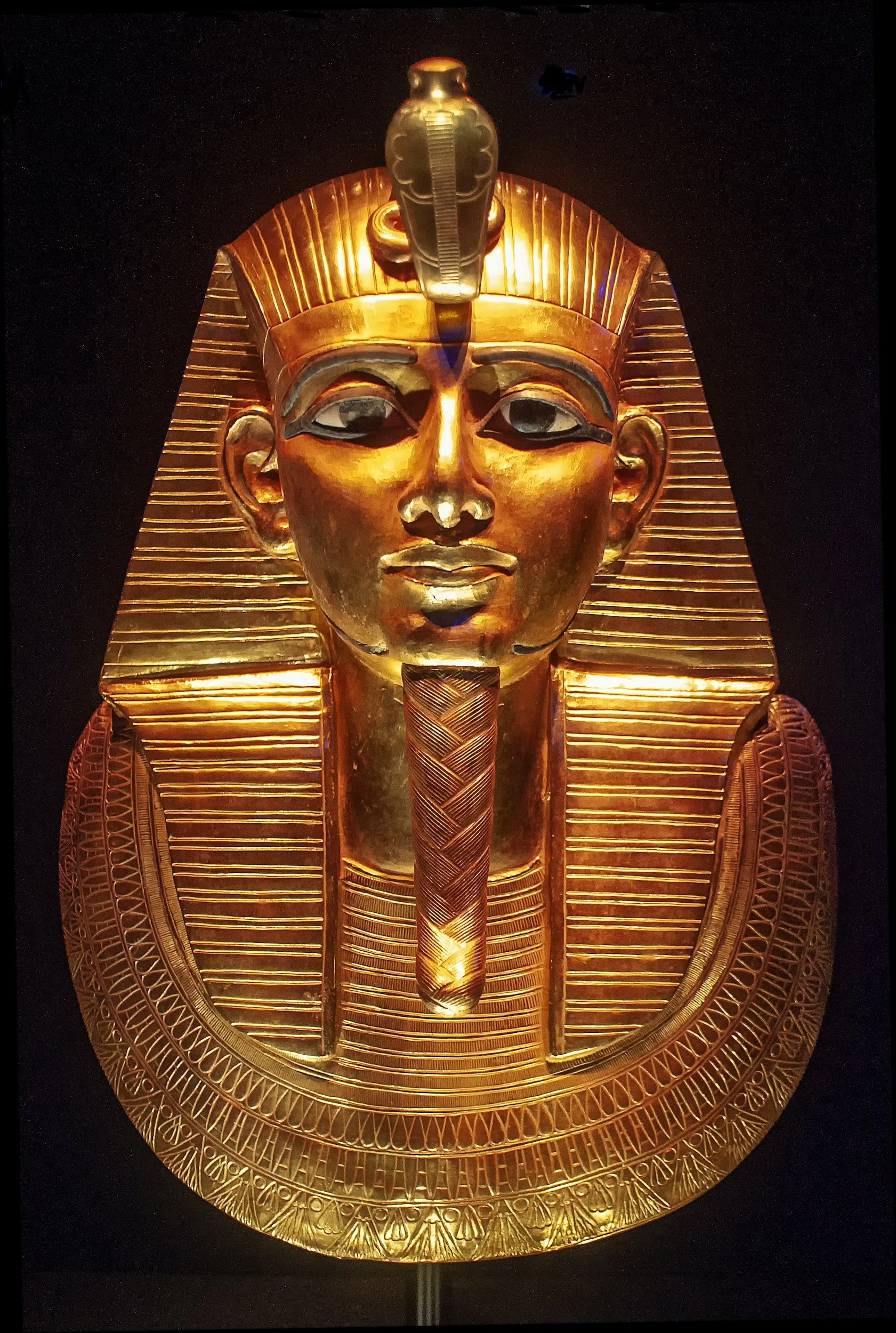 Golden mask of an ancient Egyptian pharaoh with detailed headdress and collar.