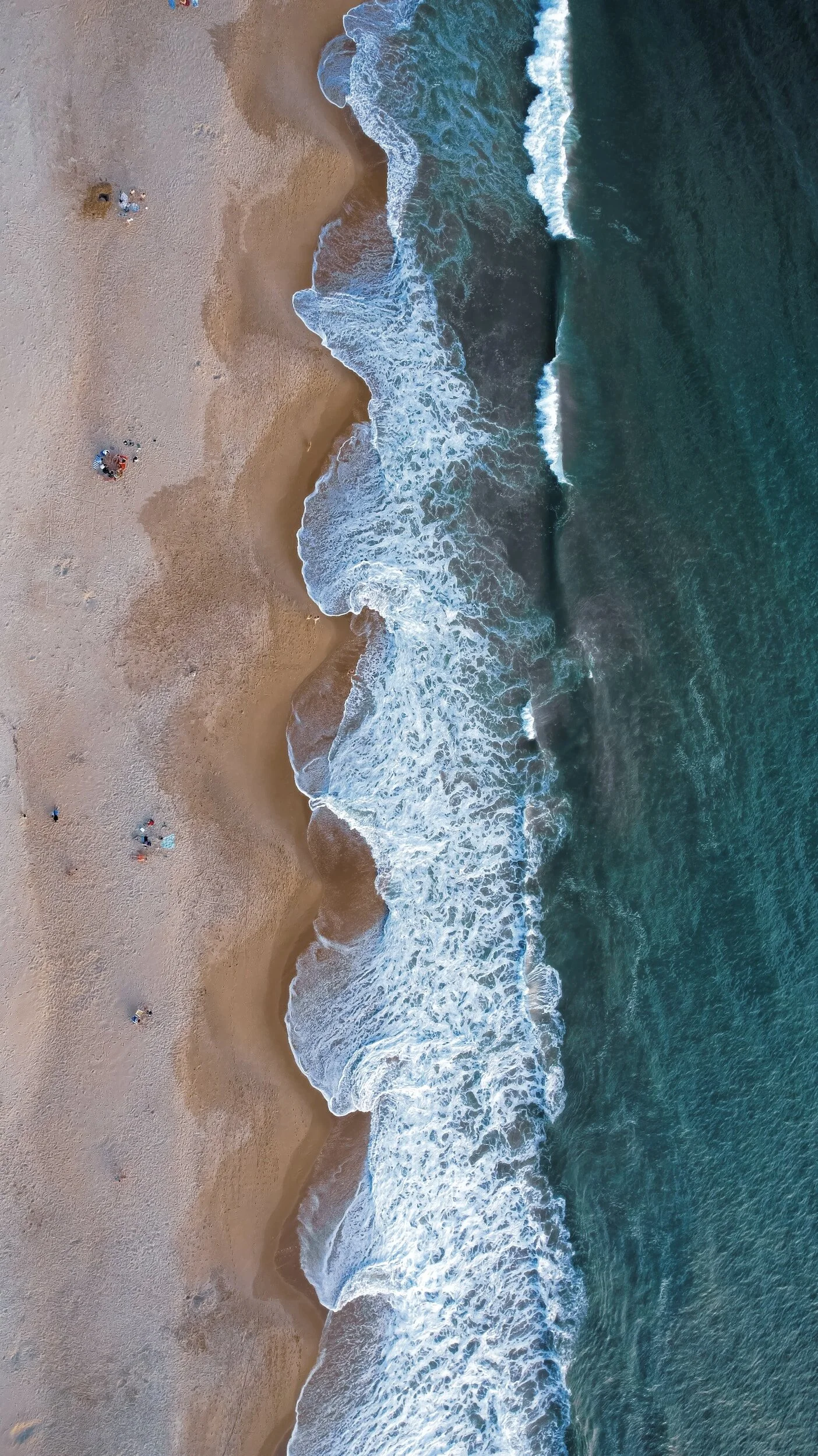 Aerial view of a beach with waves crashing onto the shore.