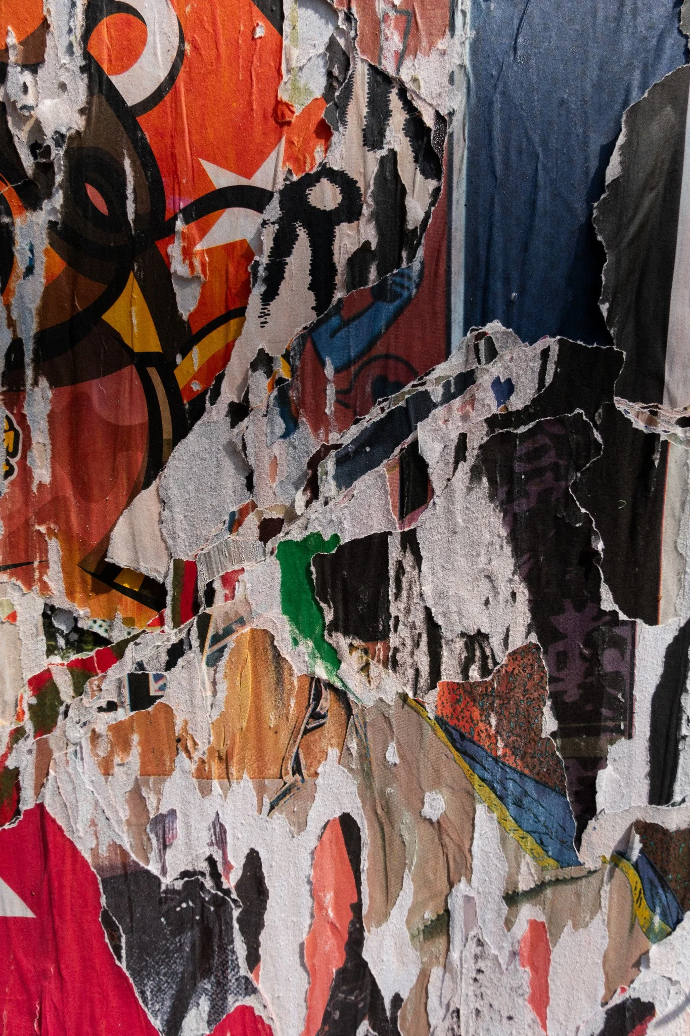 Abstract photograph of lose-up of a torn, peeling poster or paper with graffiti-style artwork and vibrant colors.