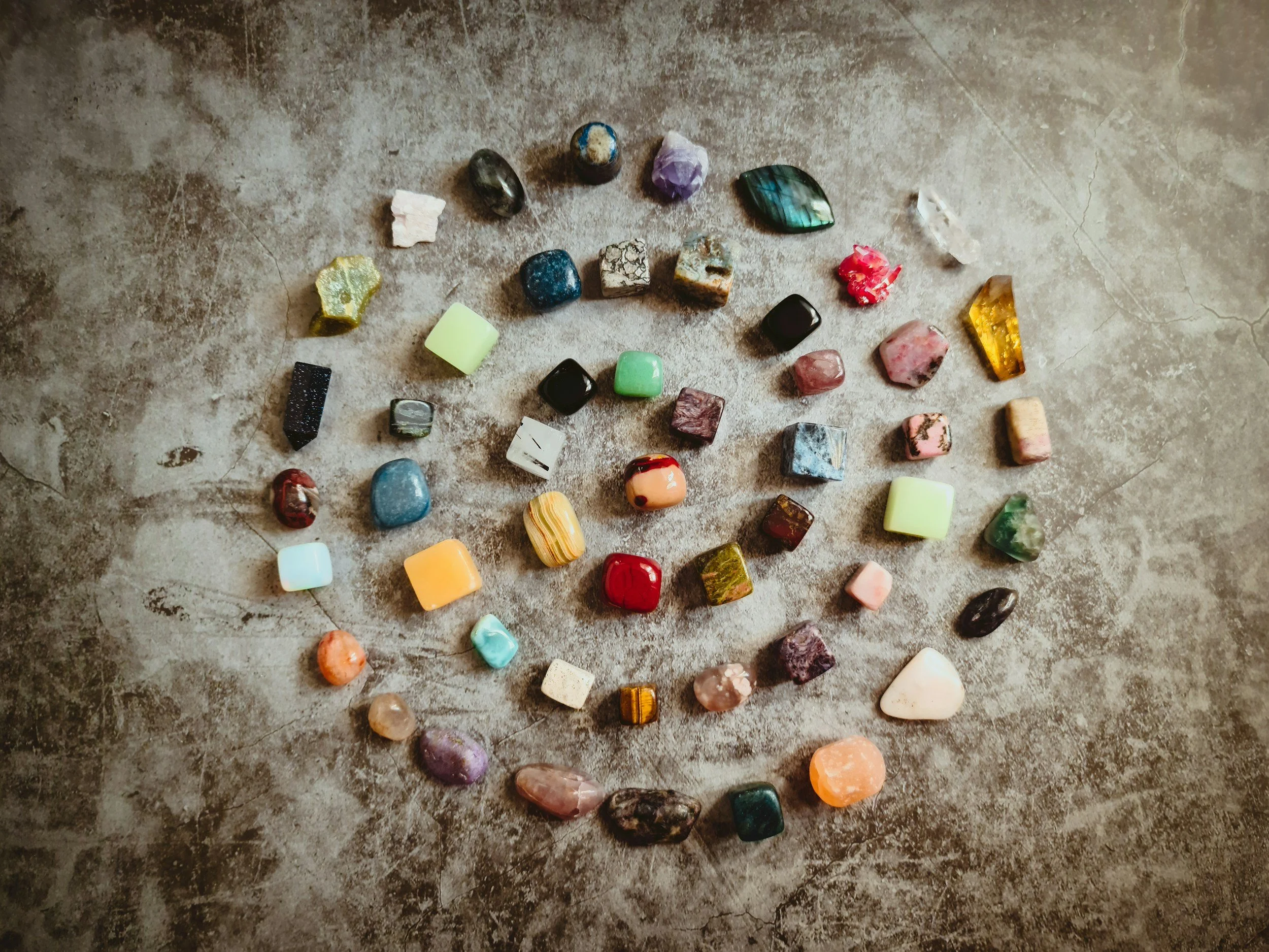 Spiral arrangement of small stones in varied colors on a neutral surface