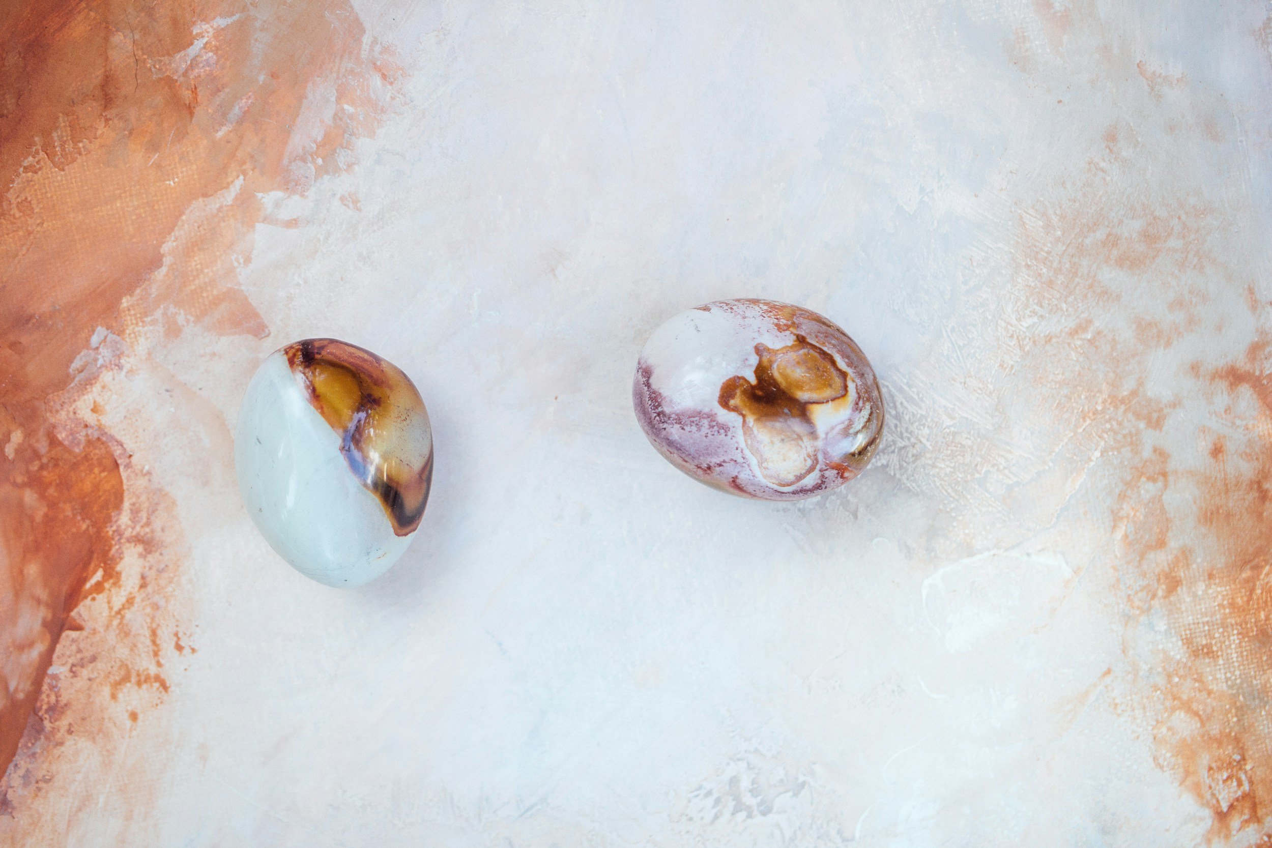 Two smooth stones placed on a softly textured surface in warm, neutral tones