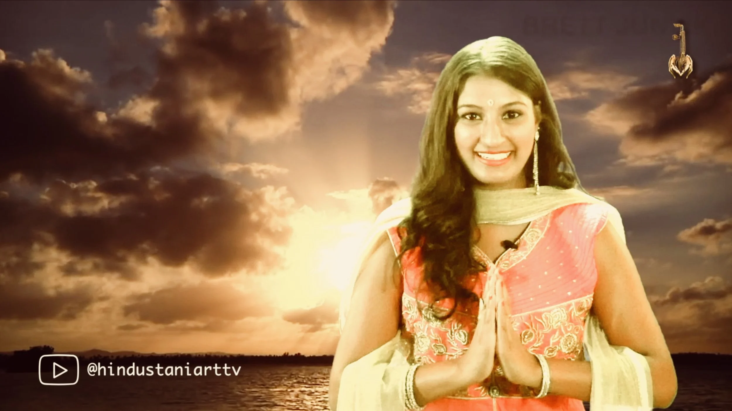Hindustani Art TV presenter against a warm, cloudy backdrop.