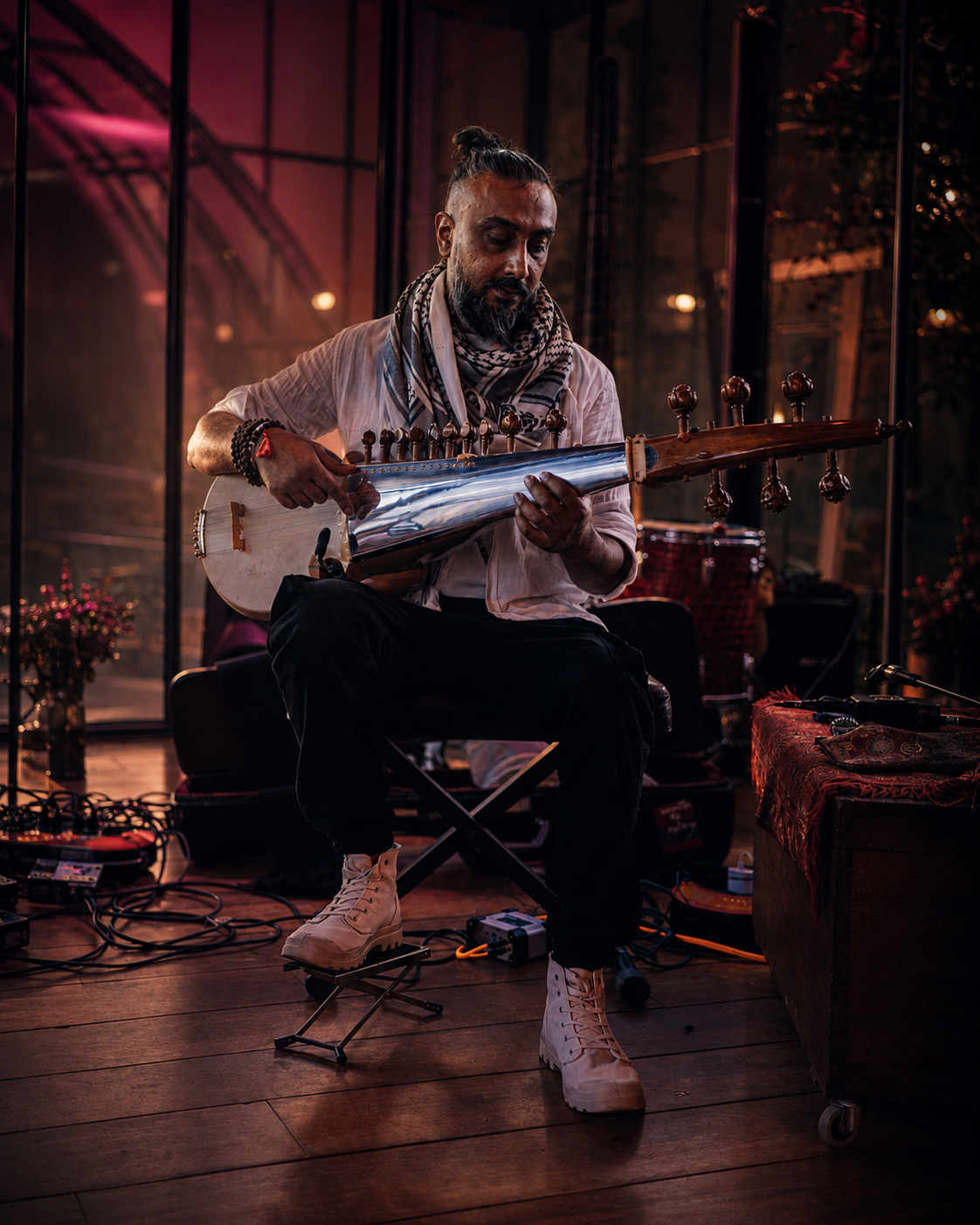 Avi Kishna performing sarod with electronic pedals and cables in an intimate venue.