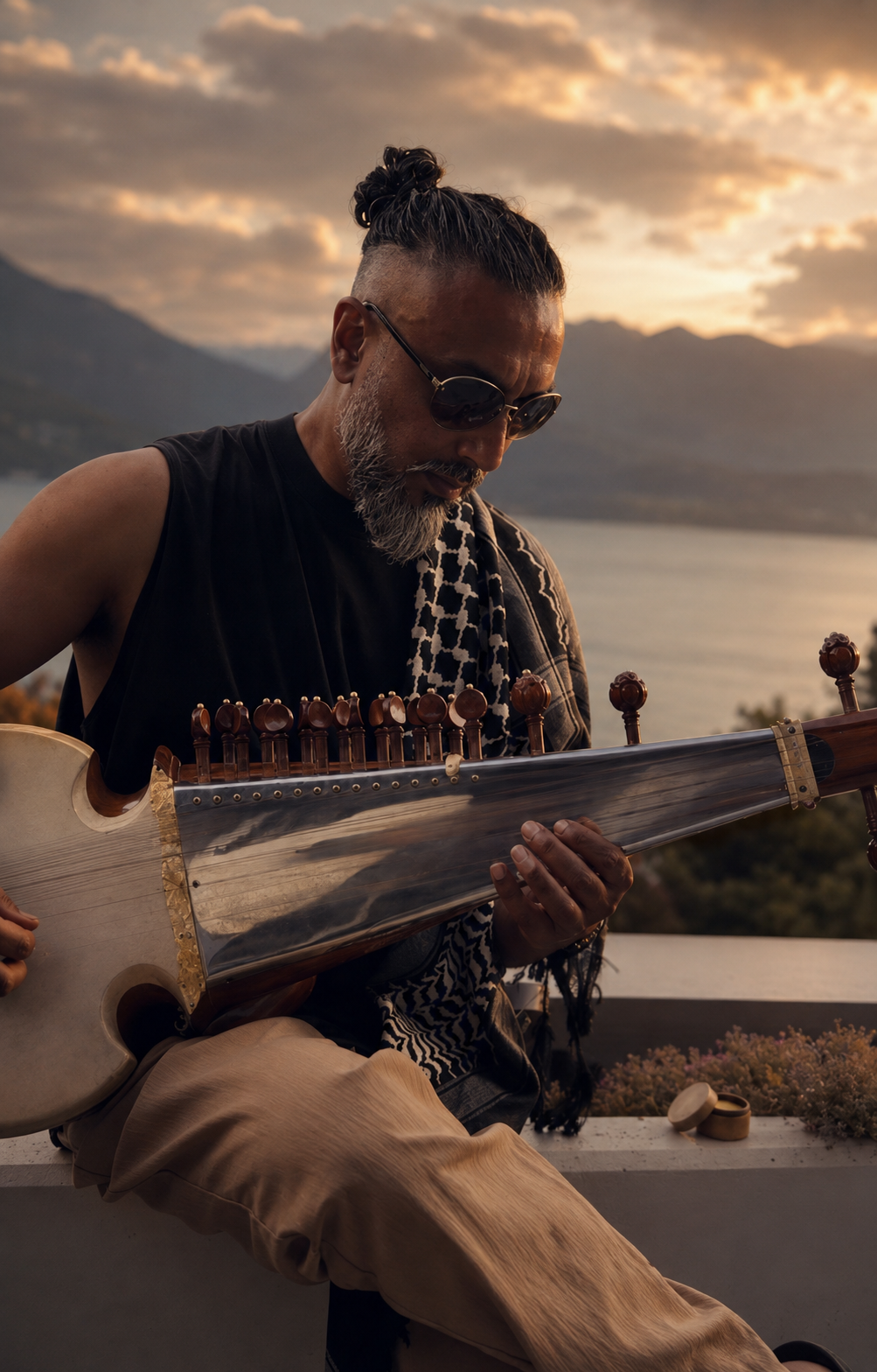 Avi Kishna playing sarod beside a mountain lake at sunset.