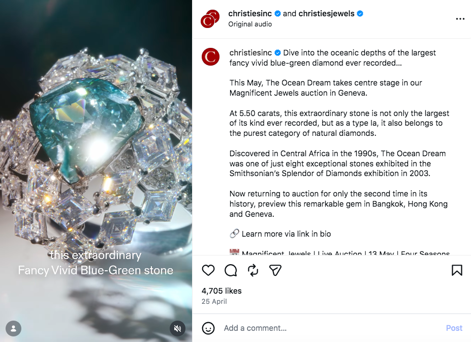 A close-up of a large, sparkling green-blue diamond surrounded by smaller white diamonds. Light reflects against it to make the precious stones dazzle.