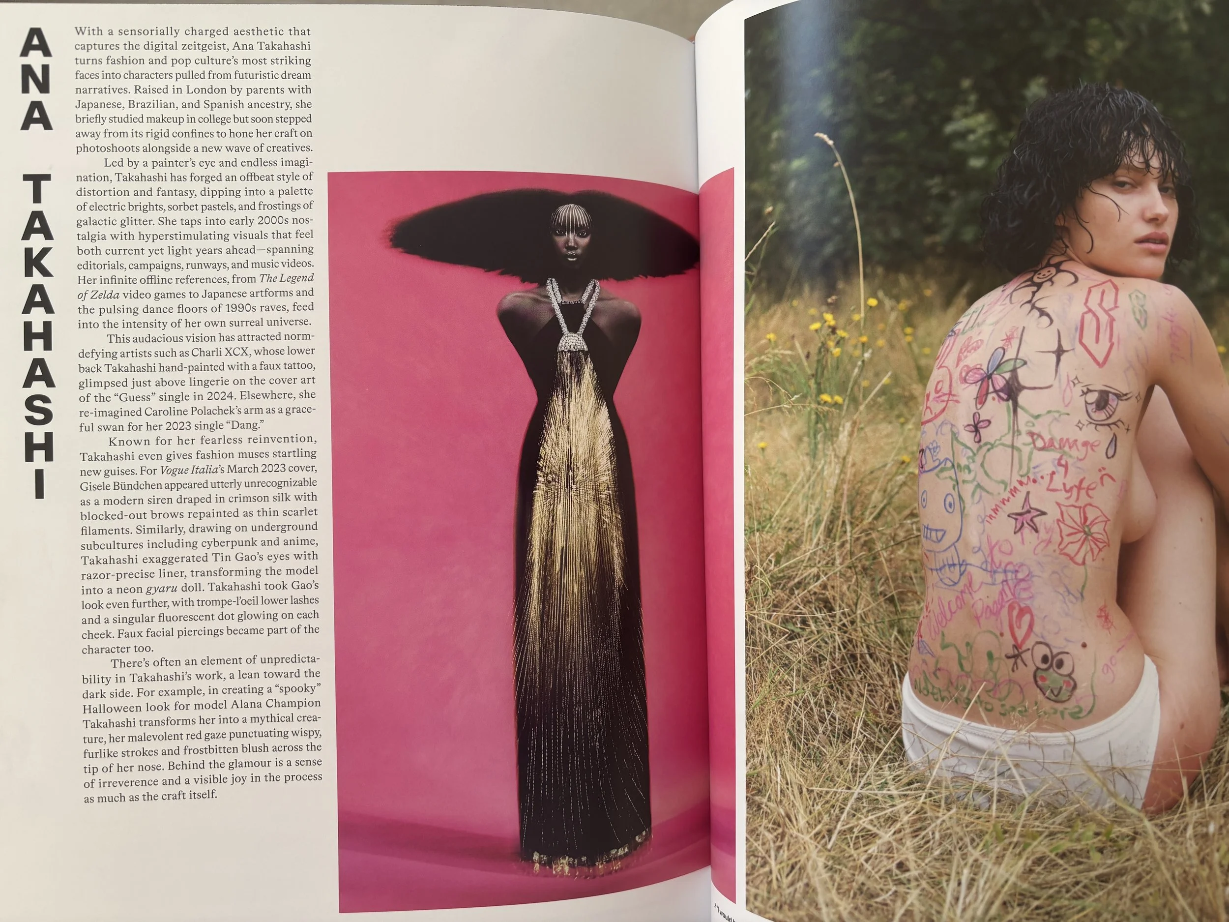 Ana Takahashi feature: a tall woman in a gold dress with sculptural afro hair and lines of pigment painted down the forehead, and the back of a person covered with multicoloured playful doodles.