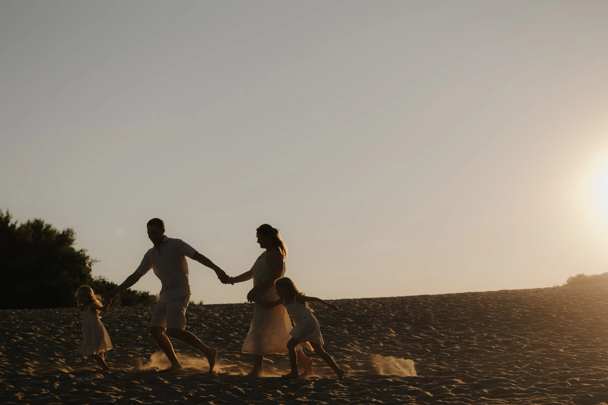 Familie läuft am Strand bei Sonnenuntergang.