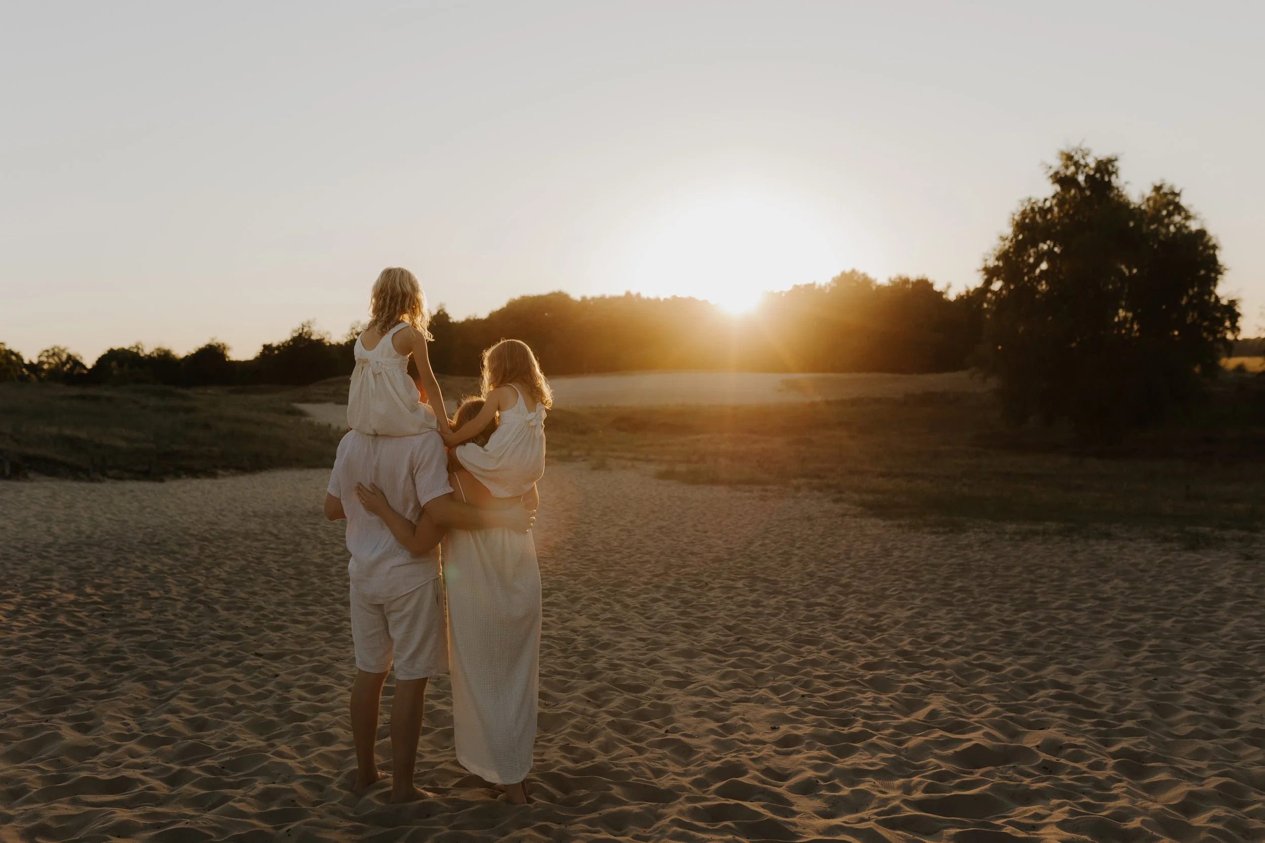 Familie mit zwei Kindern am Strand bei Sonnenuntergang.