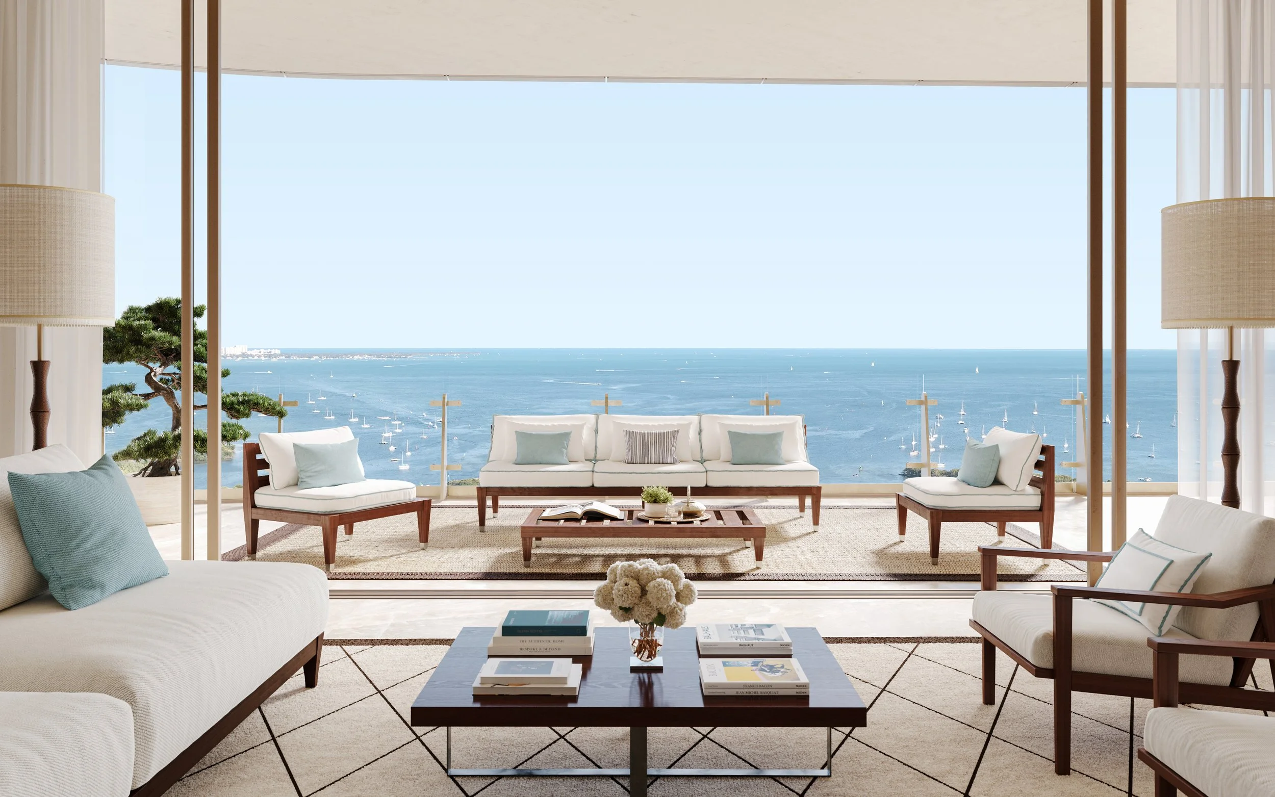 Luxurious living room with modern furniture overlooking an ocean view, featuring large glass windows, white sofas with light blue pillows, a wooden coffee table, and decorative plants.