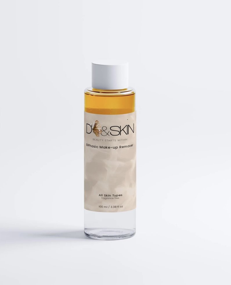 A clear plastic bottle of D & Skin bi-phasic make-up remover with a white cap, filled with yellowish liquid, on a white background.