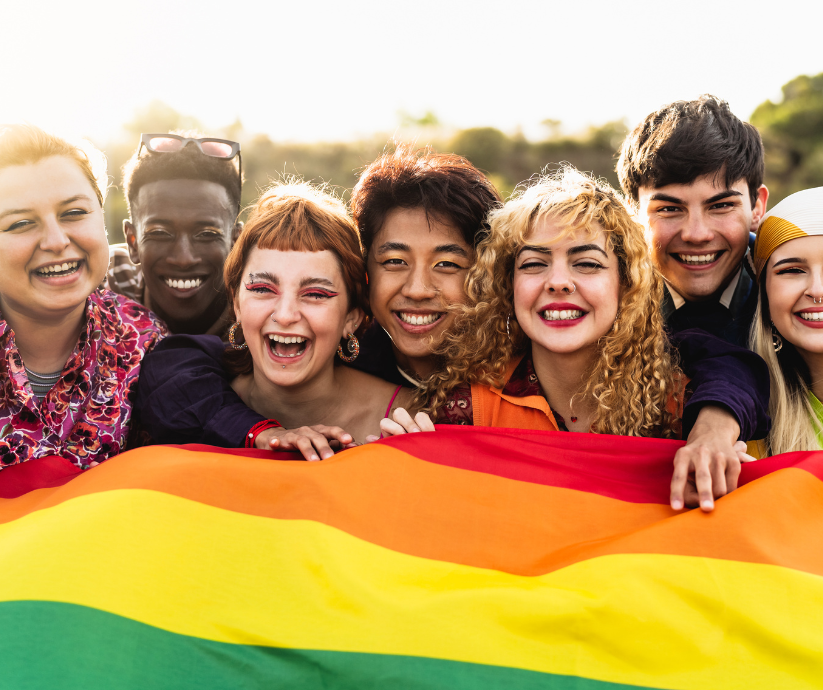 Group of friends holding LGBTQ+ flag. Devyn Box Therapy provides affirming therapy for trans, non-binary, queer & neurodivergent teens and adults.