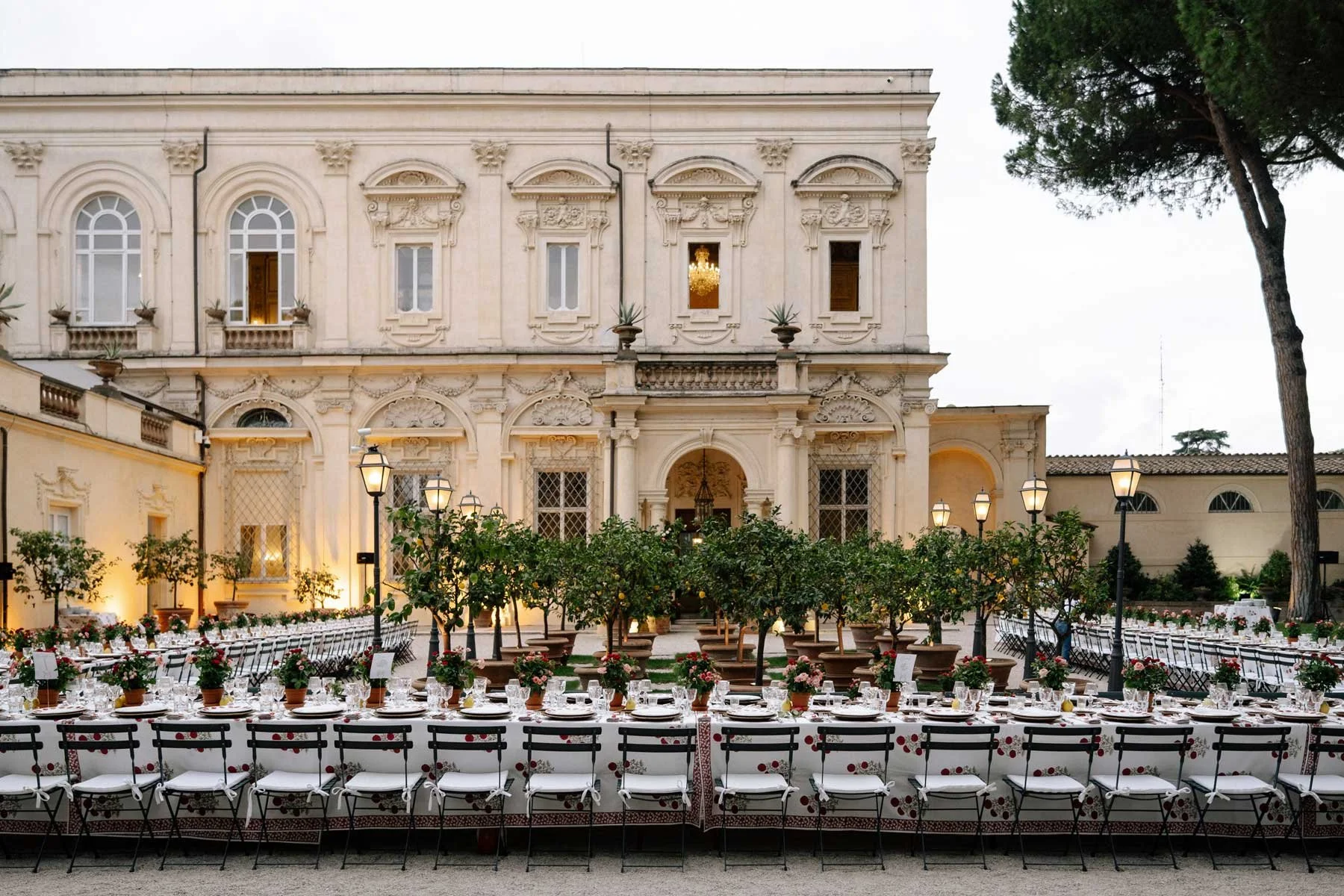 Elegant outdoor banquet with long tables and white chairs, perfect for an Italy Indian wedding by grand European architecture.