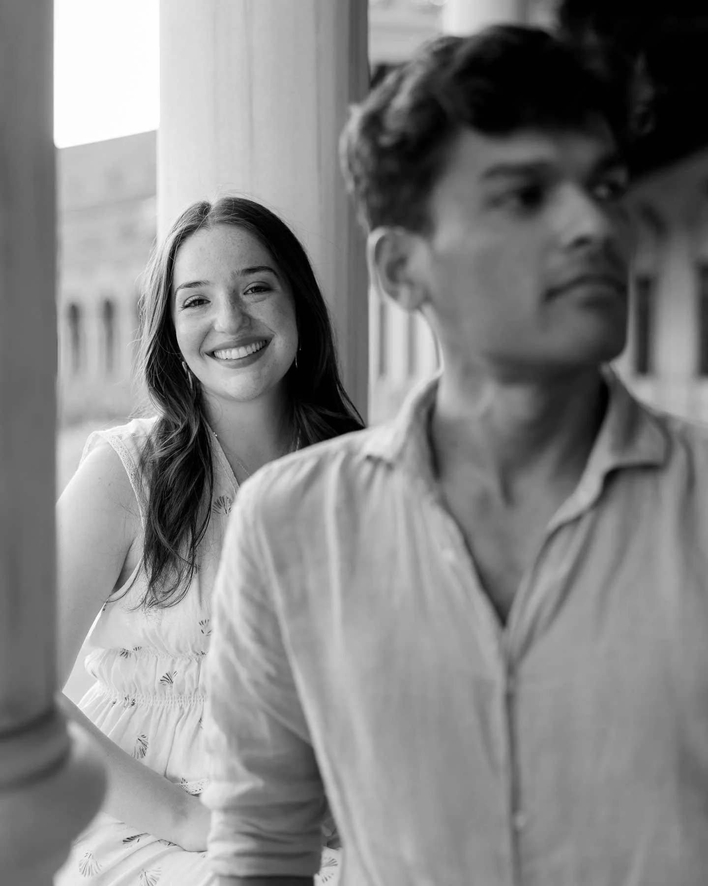 A woman smiles at the camera while a man looks away; a timeless black and white capture from a Spain destination wedding in Europe.