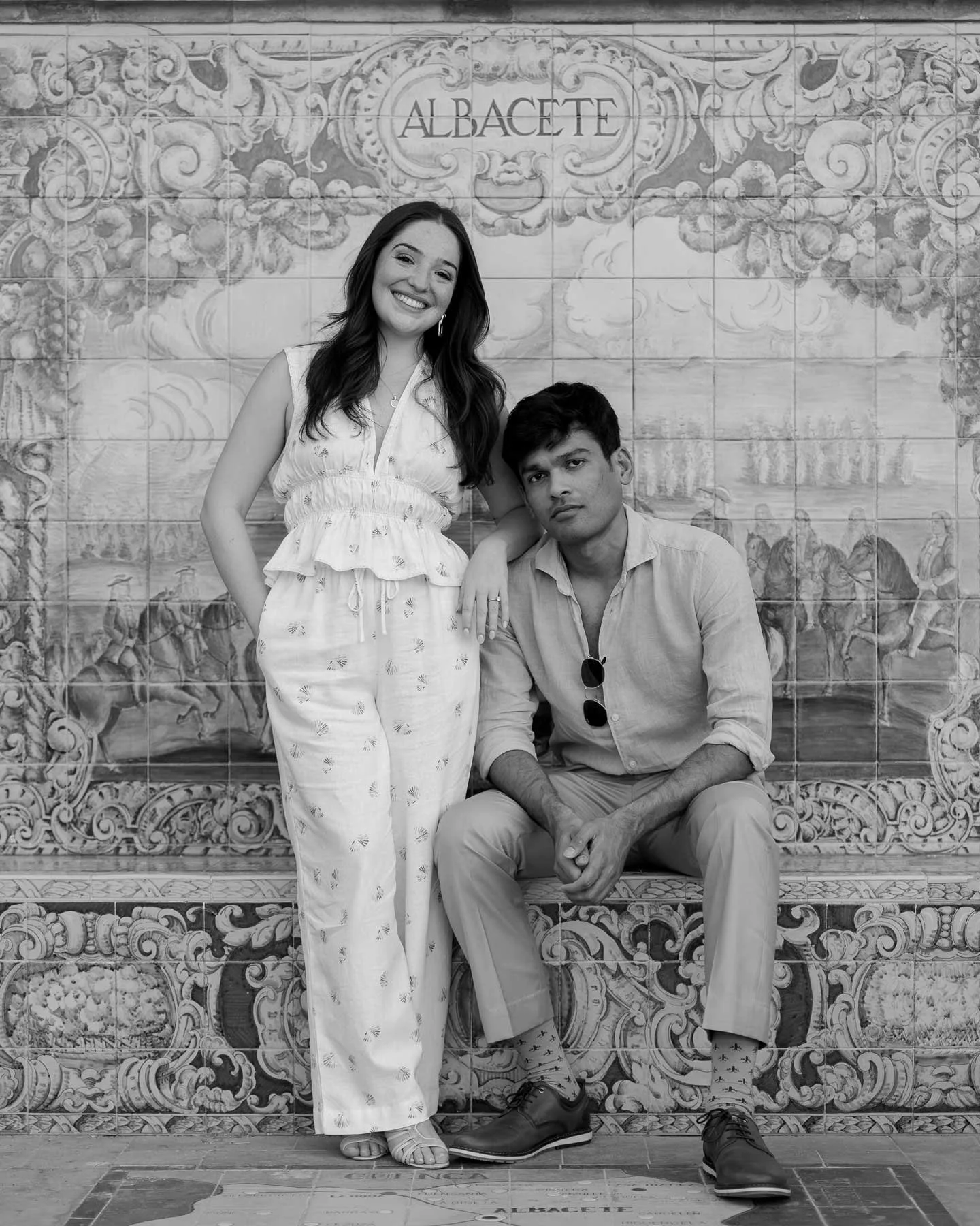 Two people pose by a tiled Albacete wall in Spain—one smiles, one sits neutral. Perfect backdrop for a Europe destination wedding.