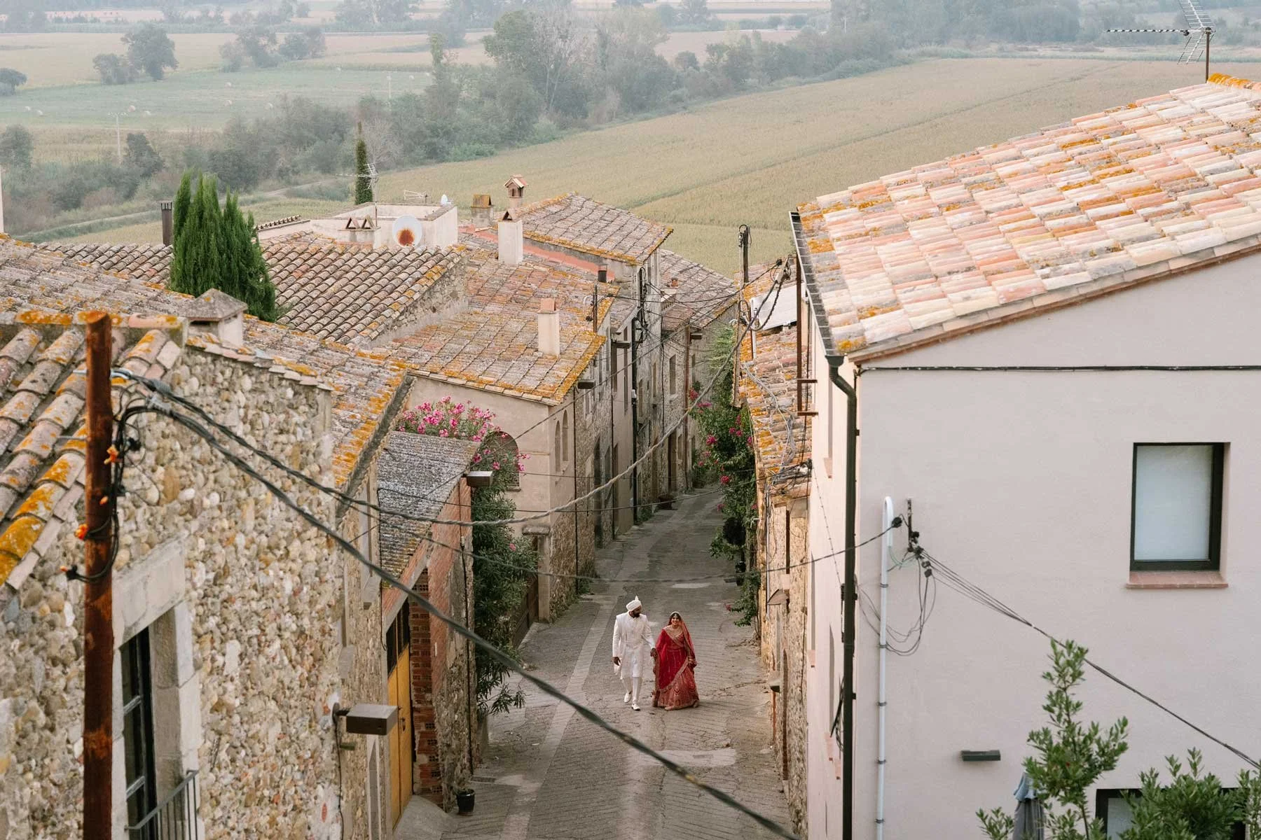 A couple walks down a cobblestone street in a rustic village—one of the top destinations for Indian weddings in Europe.