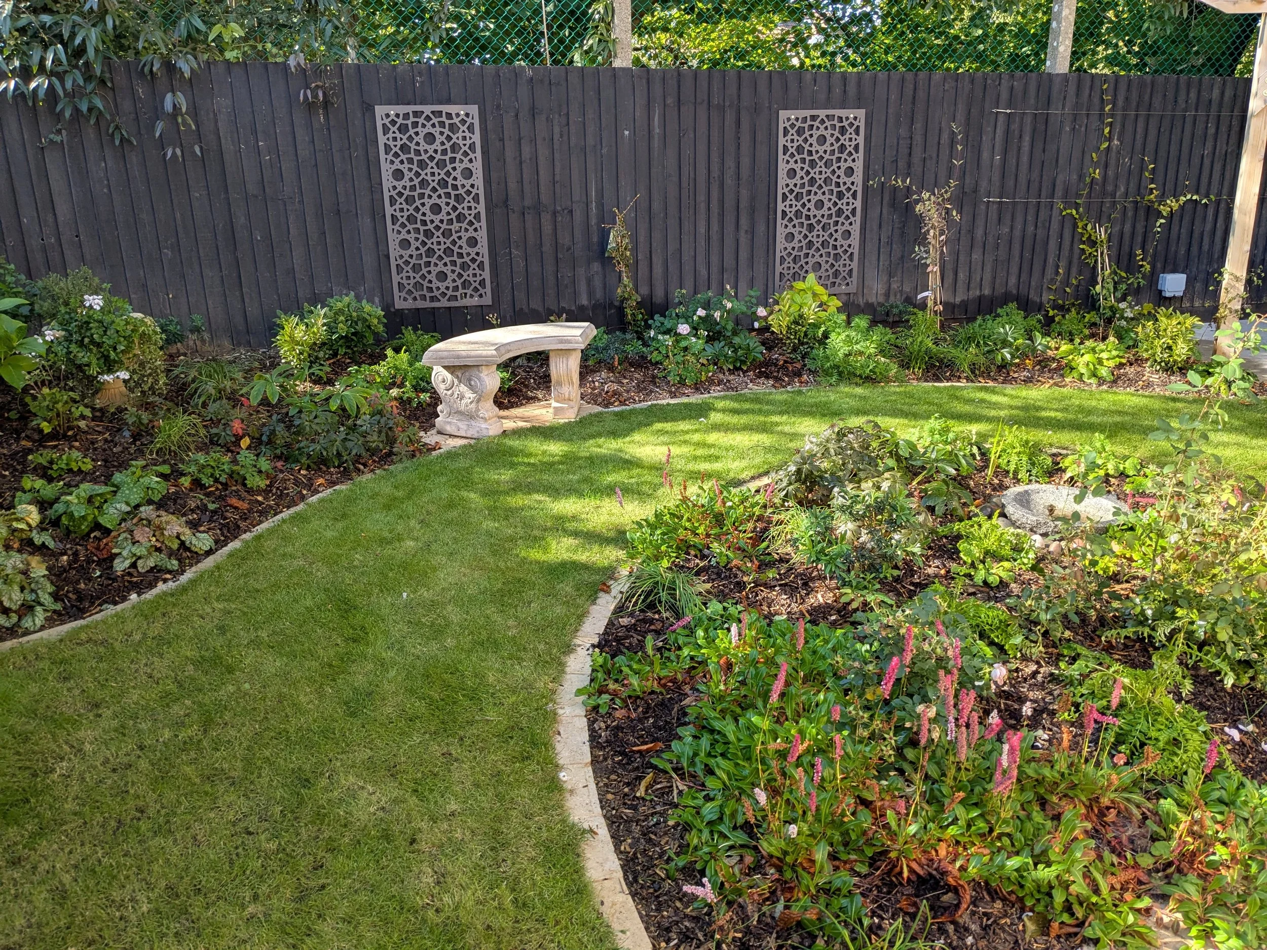 Garden with a grass path, planting and black fence