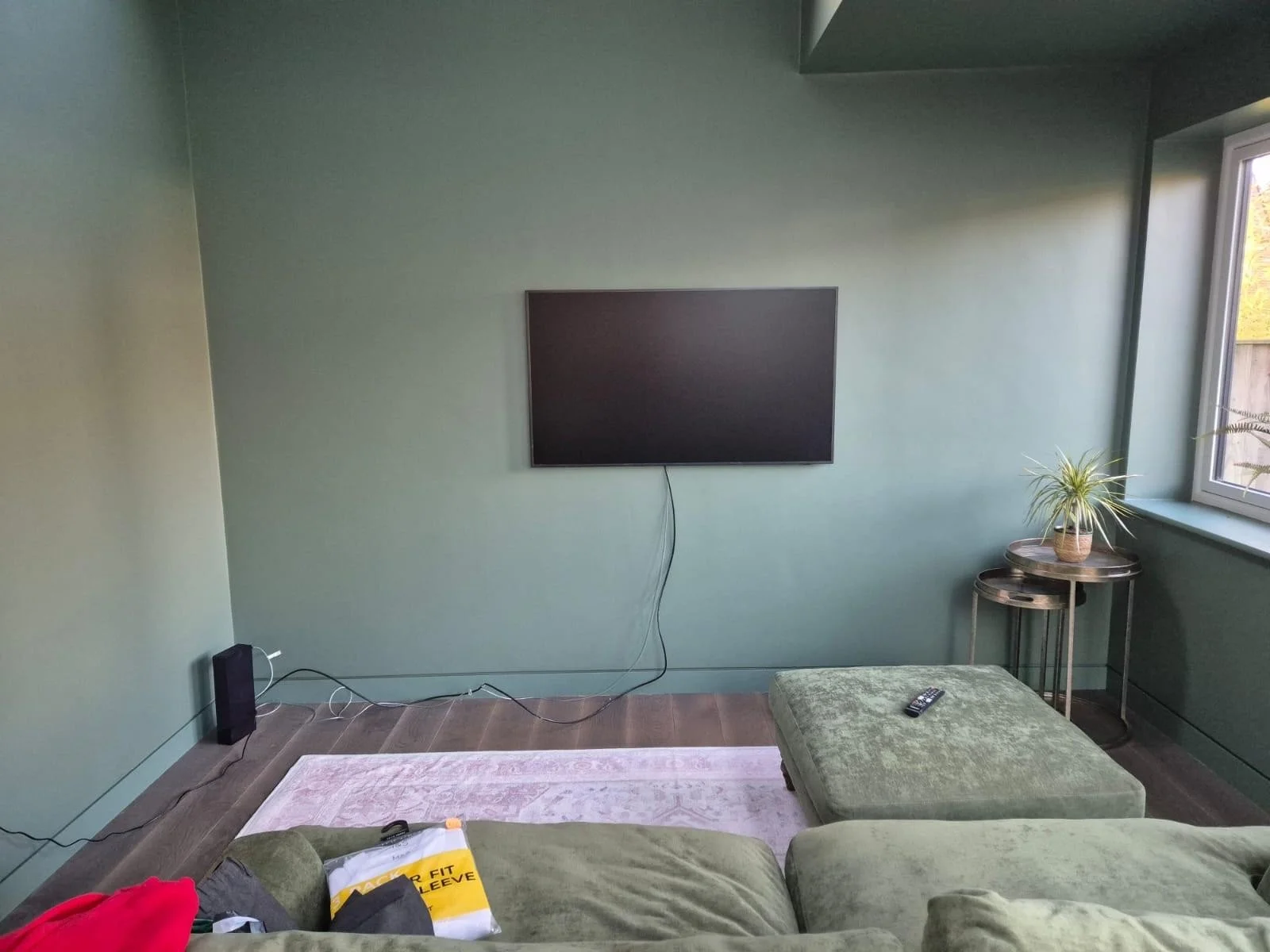 In progress: the green sitting area with a sofa, footstool and wall-mounted TV