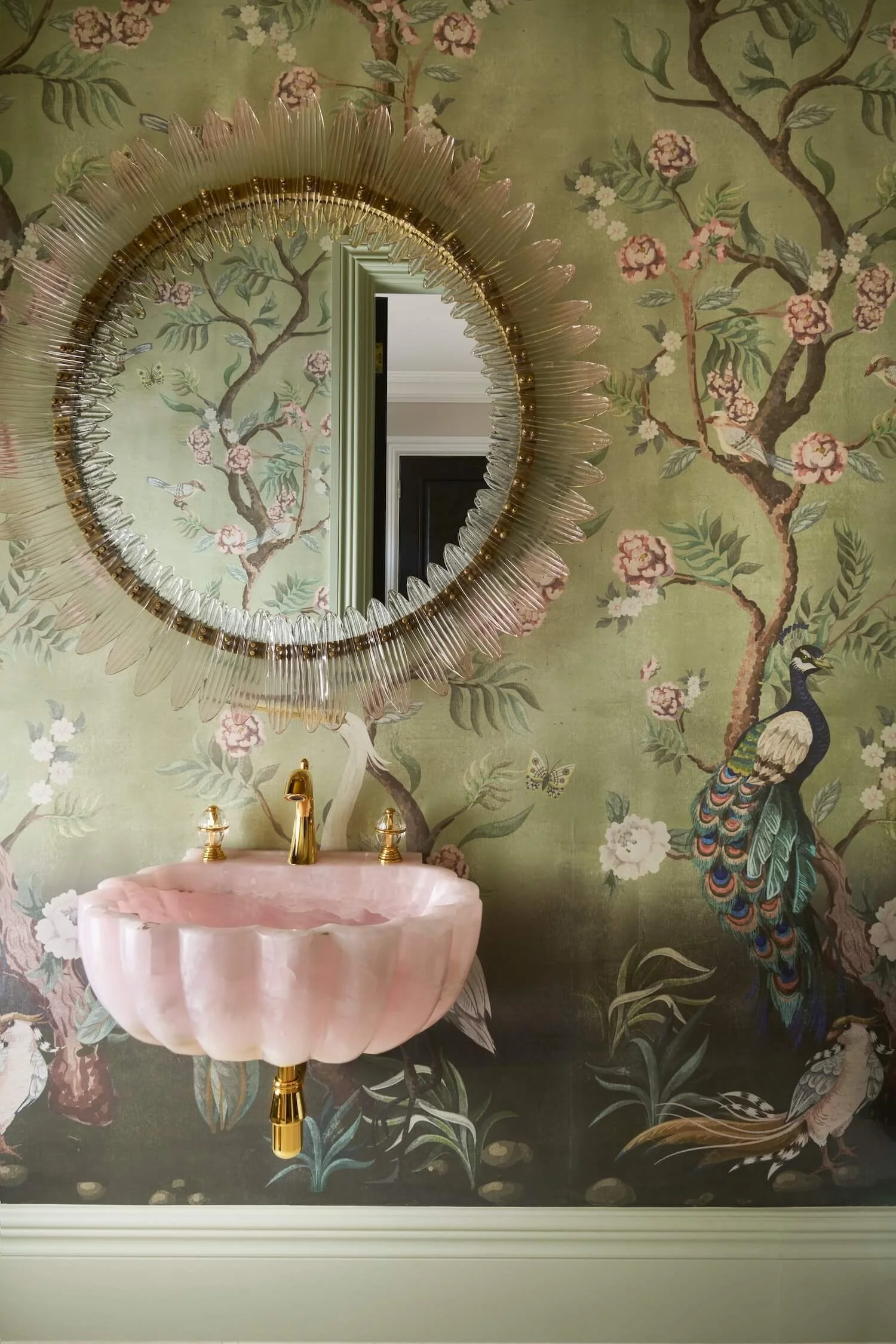 Pink stone sink against luxurious green wallpaper
