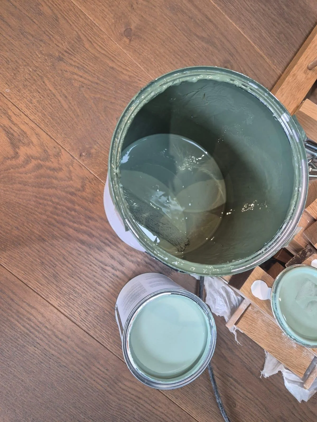 In progress: open tins of green paint on the wooden floor