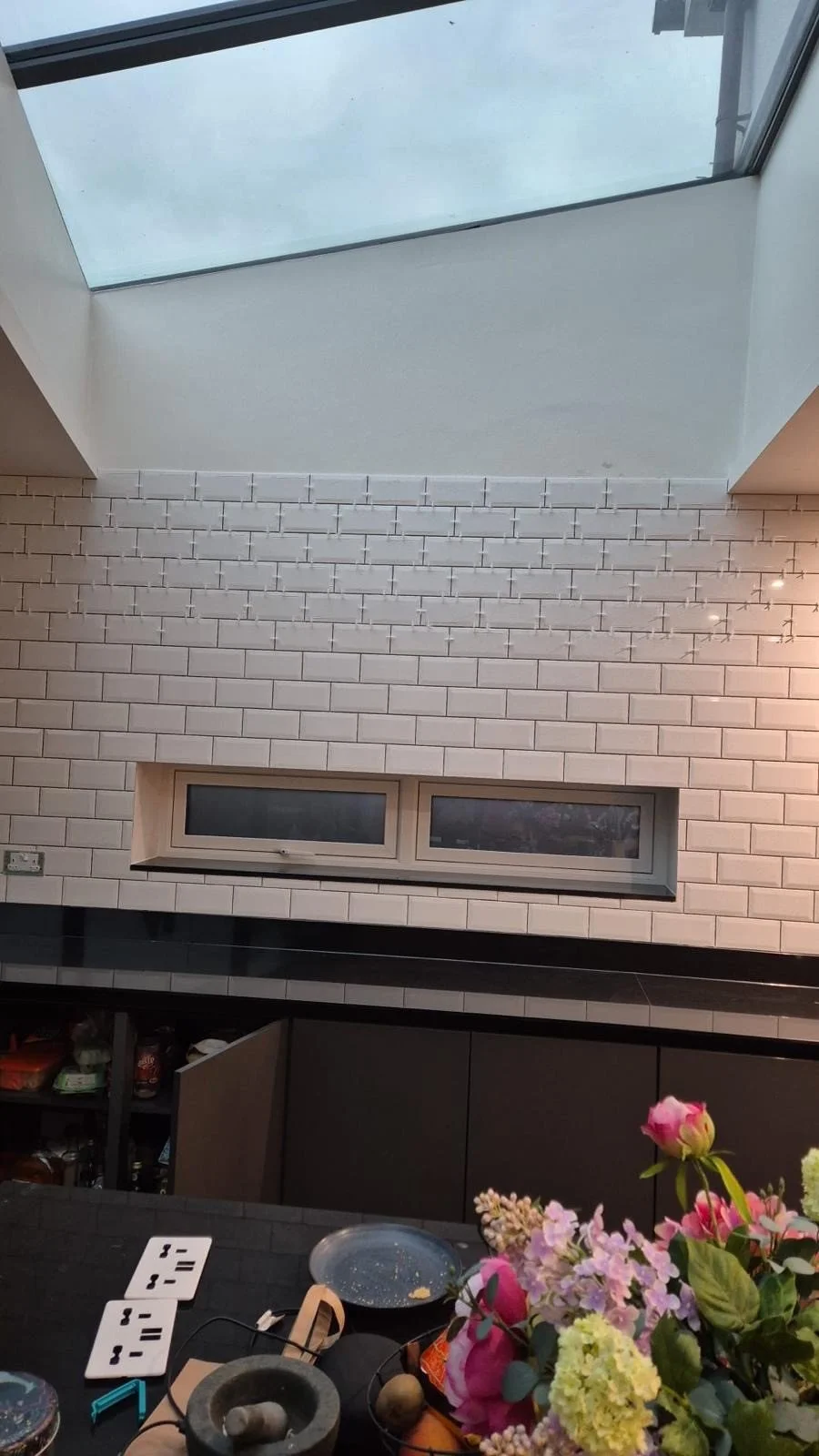 In progress: white tiles on the kitchen's back wall under the roof light