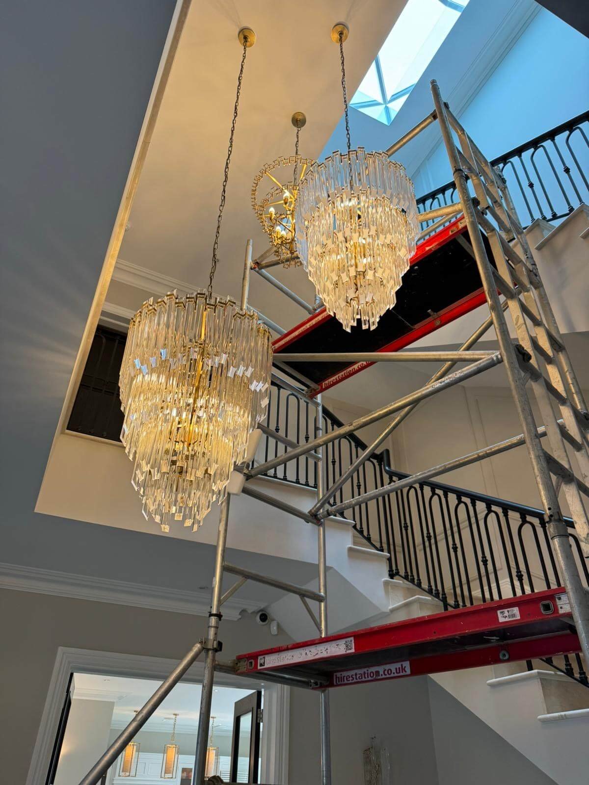 Installing the luxurious chandeliers in the entrance hall and stairway