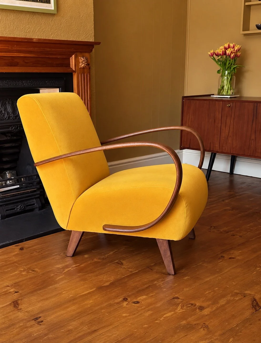 Yellow Halabala Art Deco armchair with curved wooden arms in a period interior